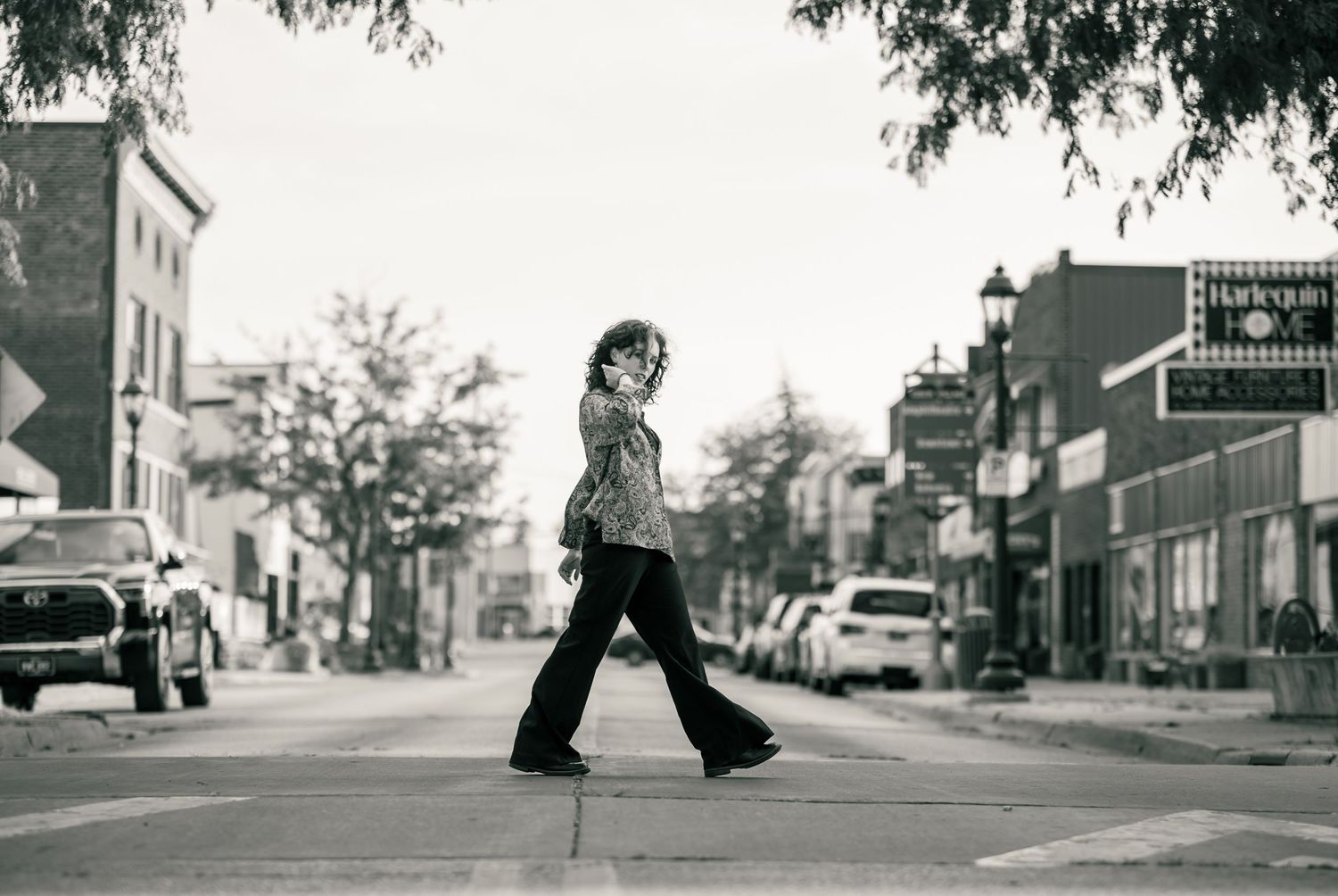 A series of black and white street photographs showing urban scenes with cars, buildings and people walking.