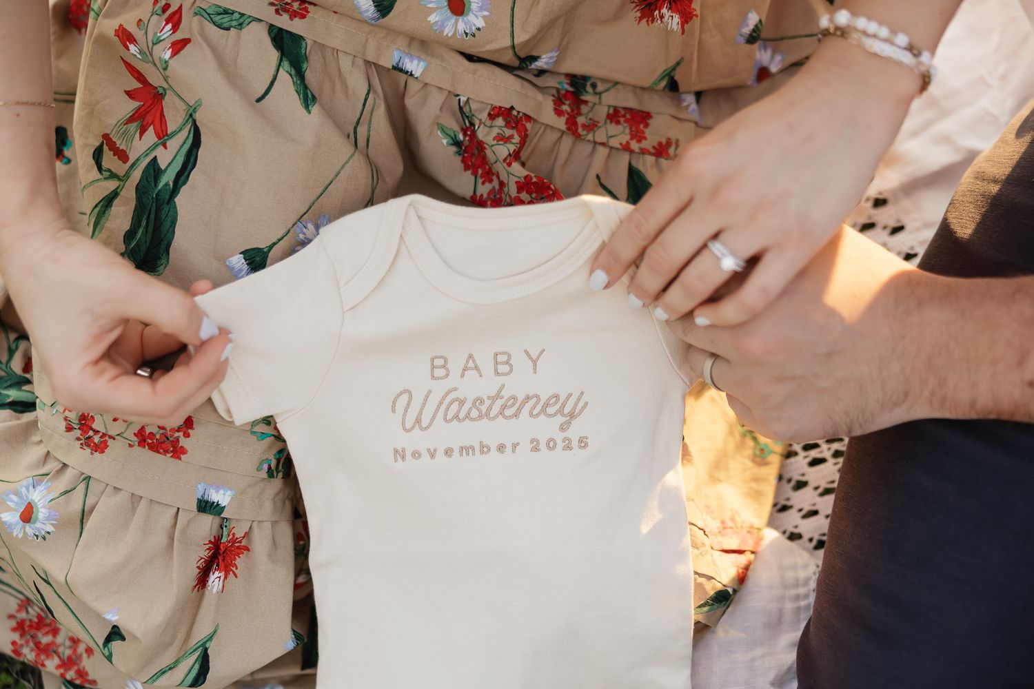 photographer overland park ks takes photo of pregnancy announcement onesie with parents hands