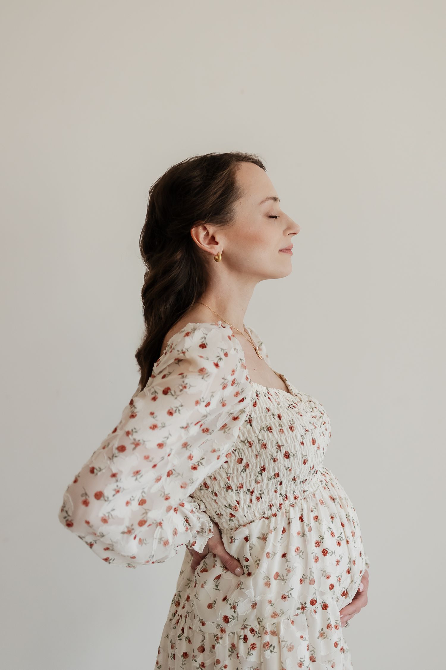 side profile of mom to be holding her baby bump with eyes closed at the studio reverie in overland park