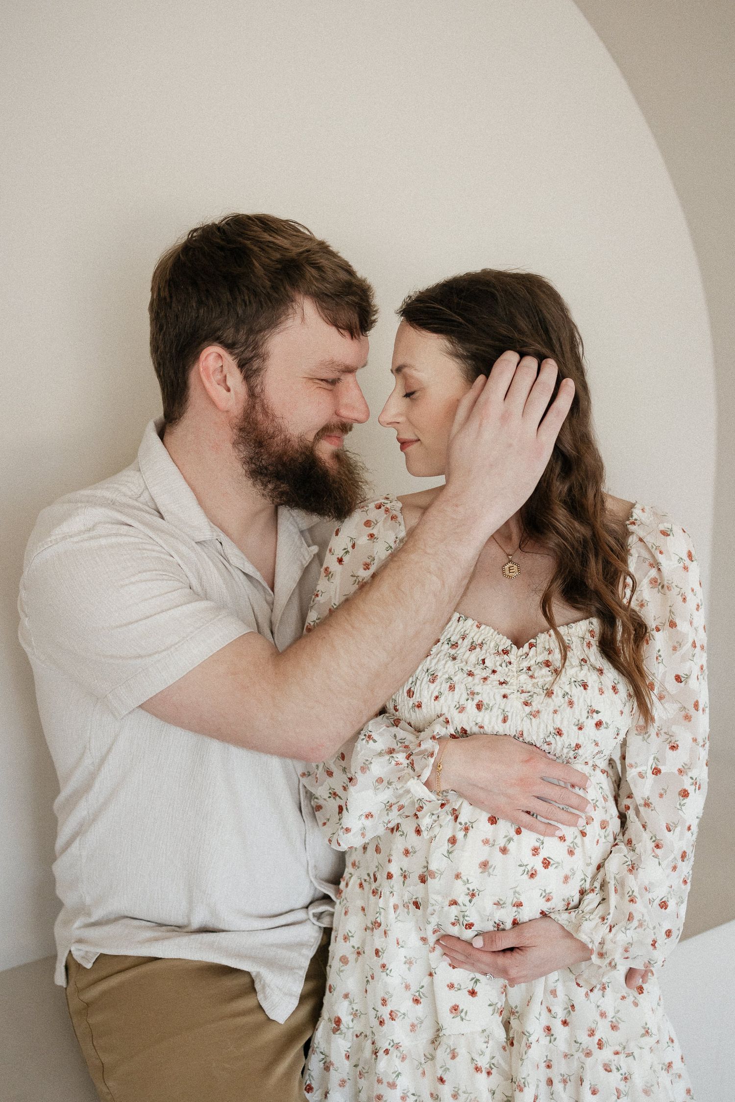 husband tucking his wife's hair behind her ear as she closes her eyes and holds her baby bumpphotographer overland park ks
