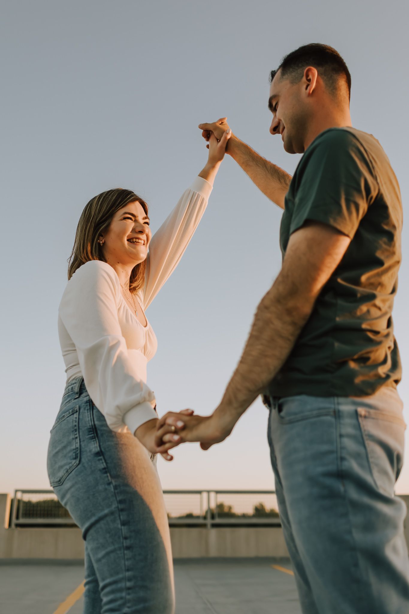 photographer overland park ks couple holding hands up in the air for artistic low angle photo featuring bright blue sky