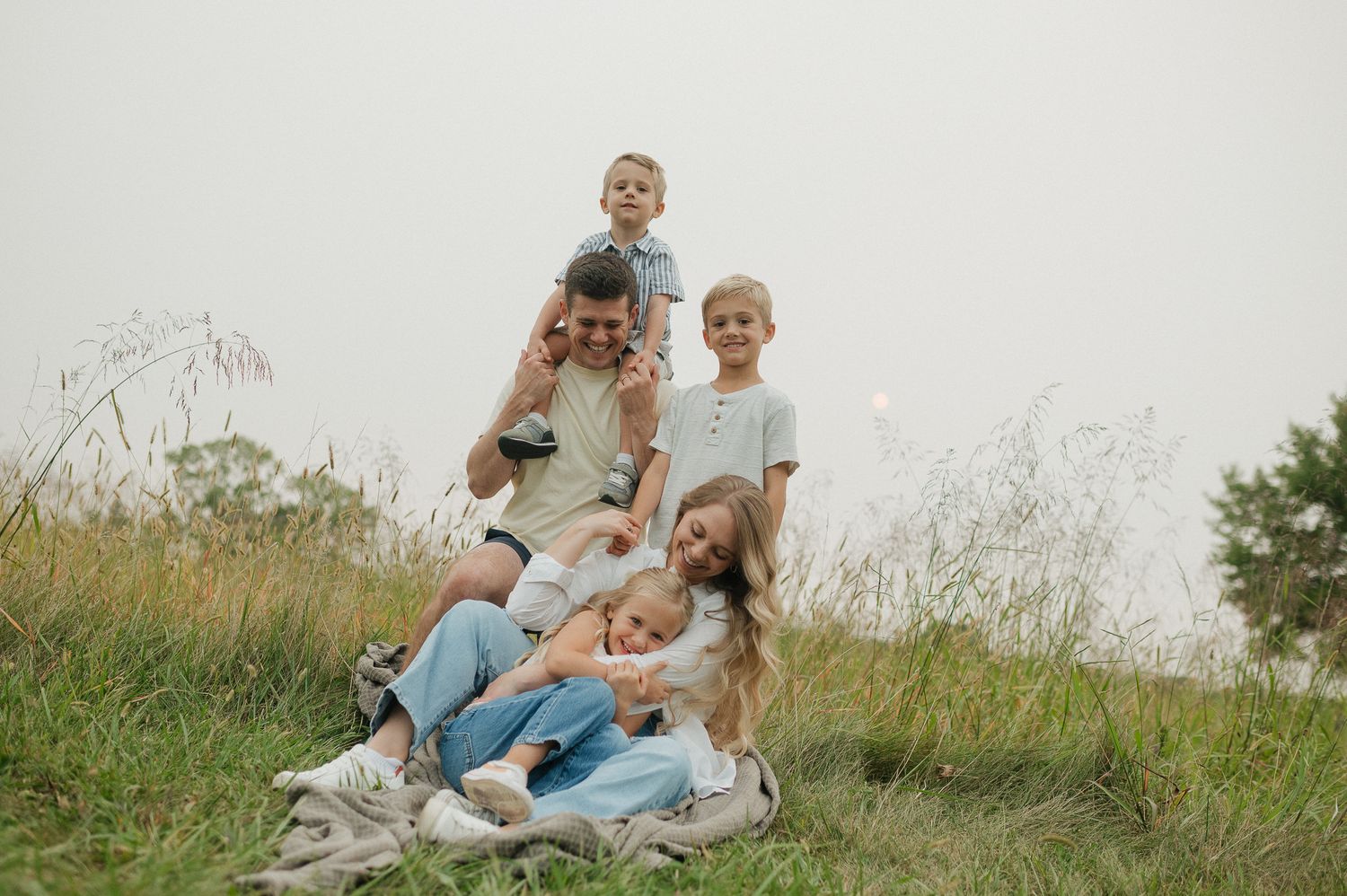 kansas city family photographer with her husband and three children in open field at shawnee mission park