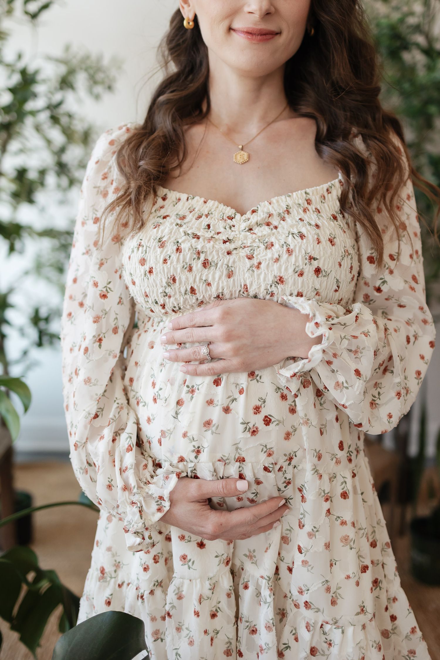 close up of mom smiling holding her baby bump with wedding ring in focus