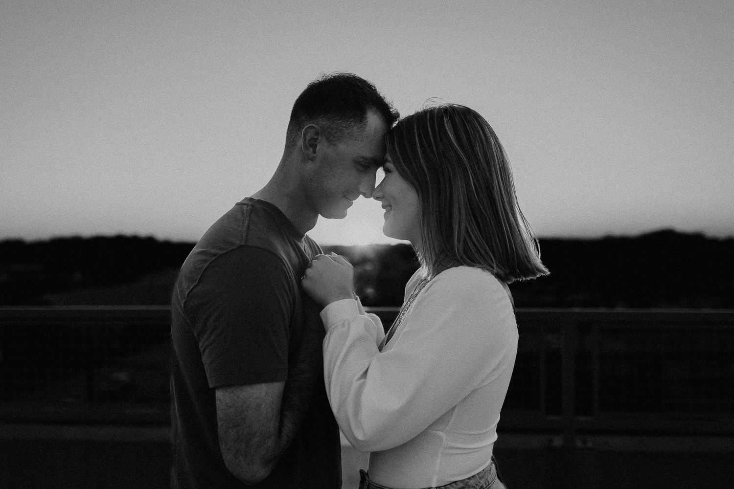 photographer overland park ks couple forehead to forehead with sunset streaming between them on parking garage rooftop