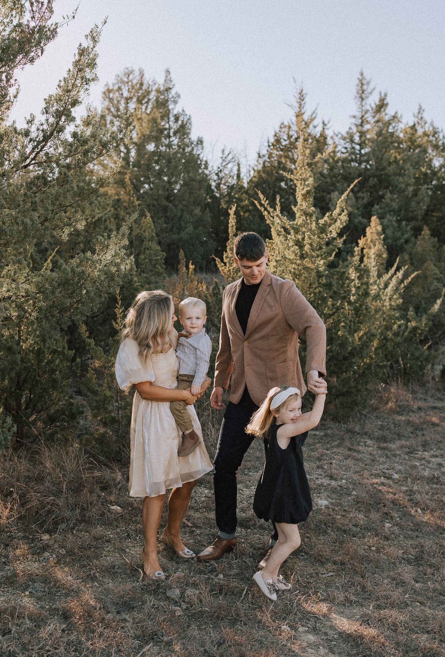 family dancing to music surrounded by green pine trees