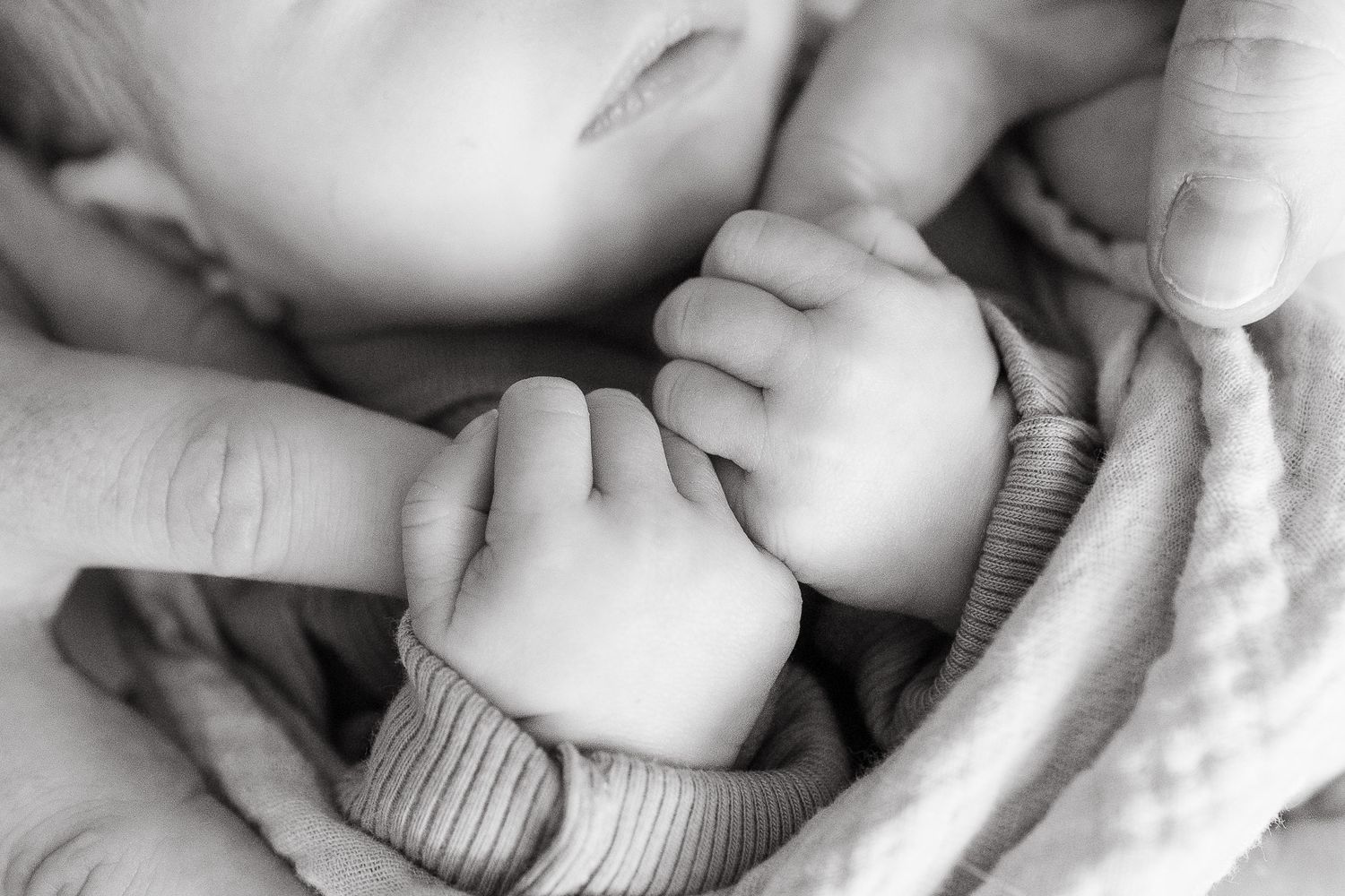 newborn baby gripping each of her parents index finger while sleeping Photographer overland park ks