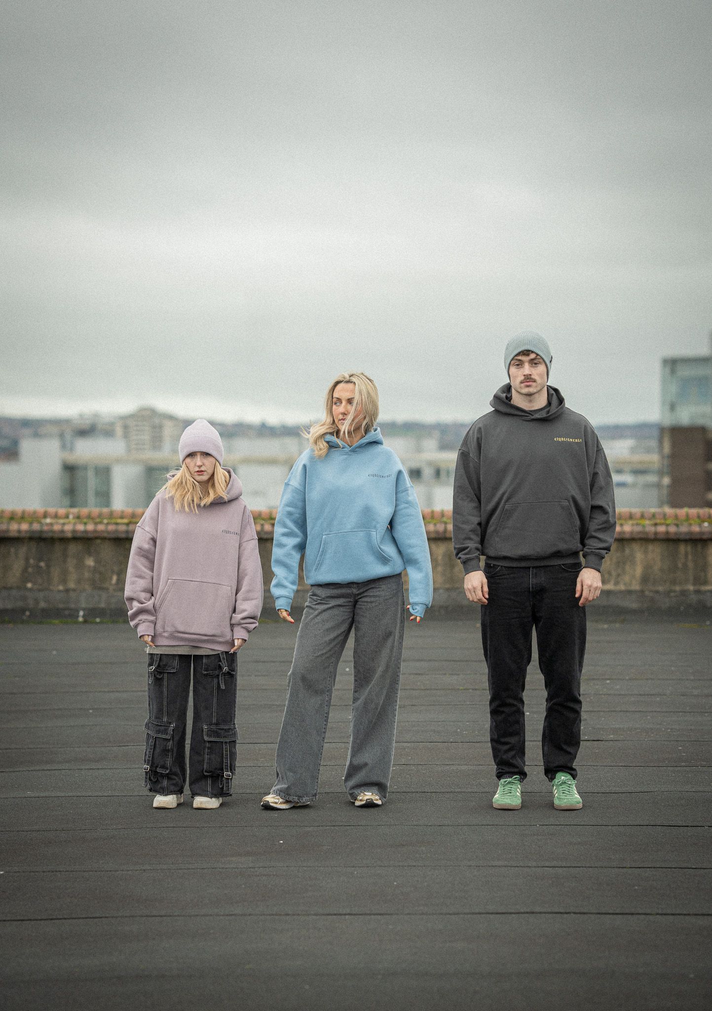 Two women and a man standing on a rooftop in an urban editorial style photoshoot for a clothing brand.