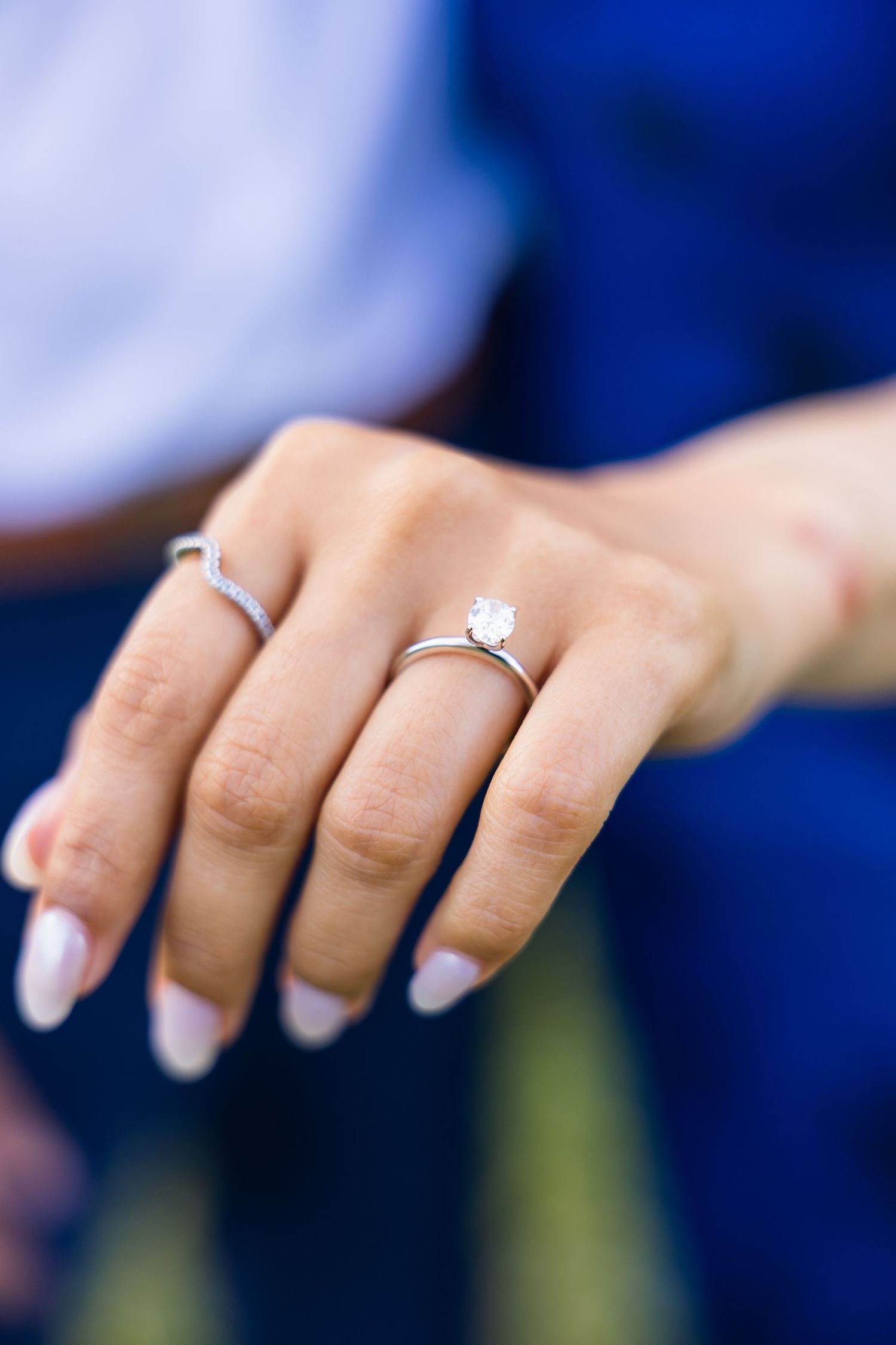 Close-up of hand displaying elegant solitaire diamond engagement ring with manicured nails.
