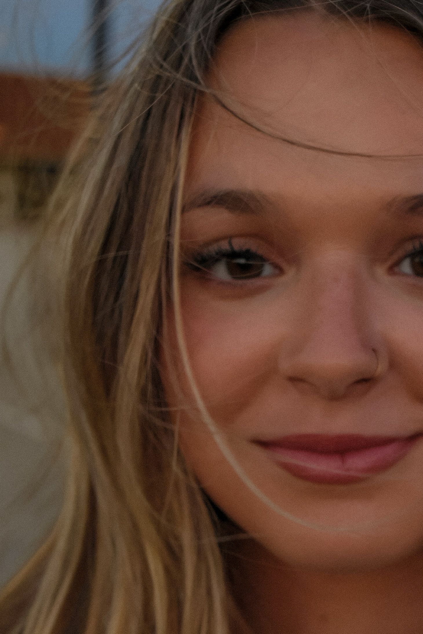 Close-up half portrait of smiling blonde woman with natural makeup at golden hour.