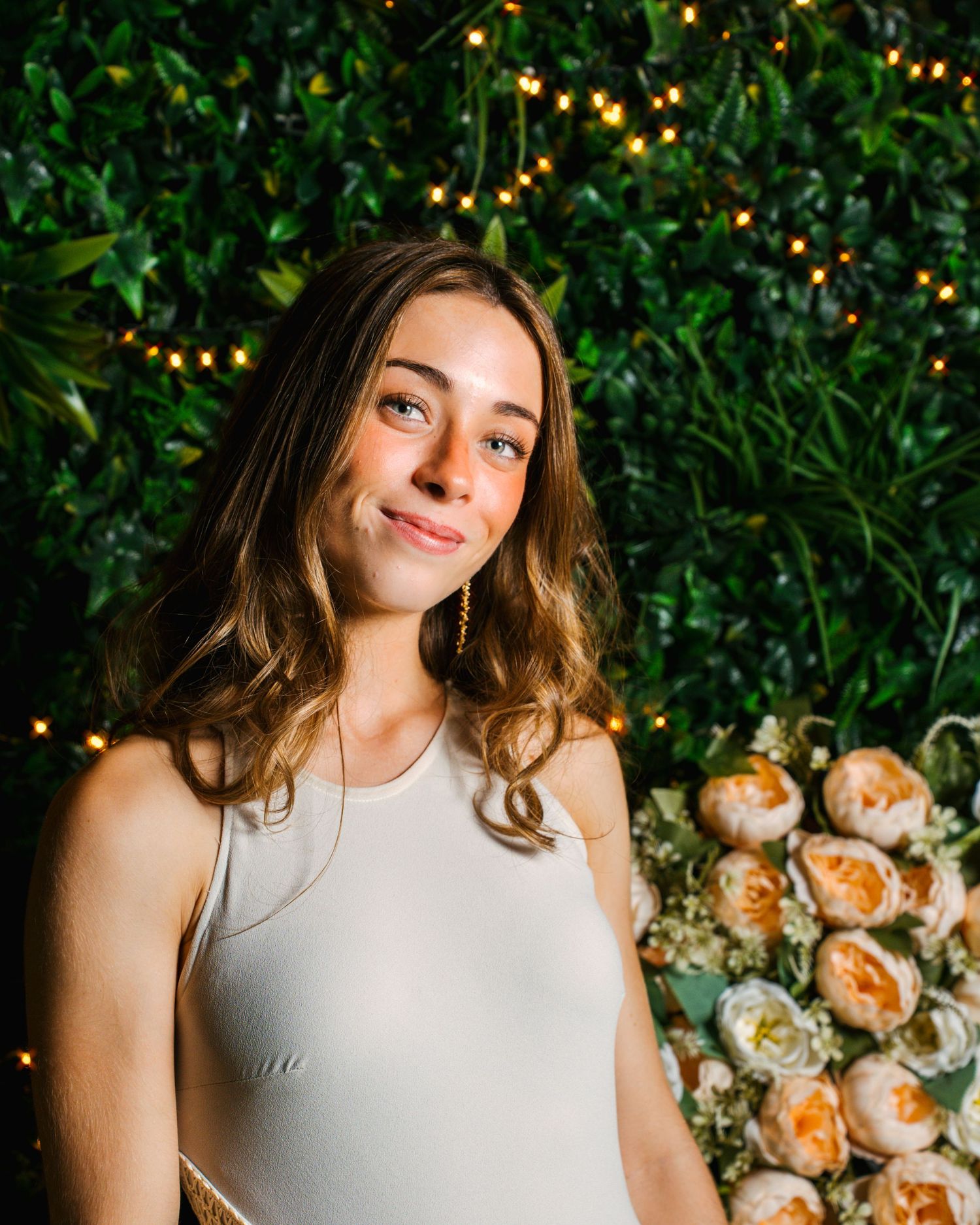 Retrato de una mujer con vestido blanco junto a flores y vegetación