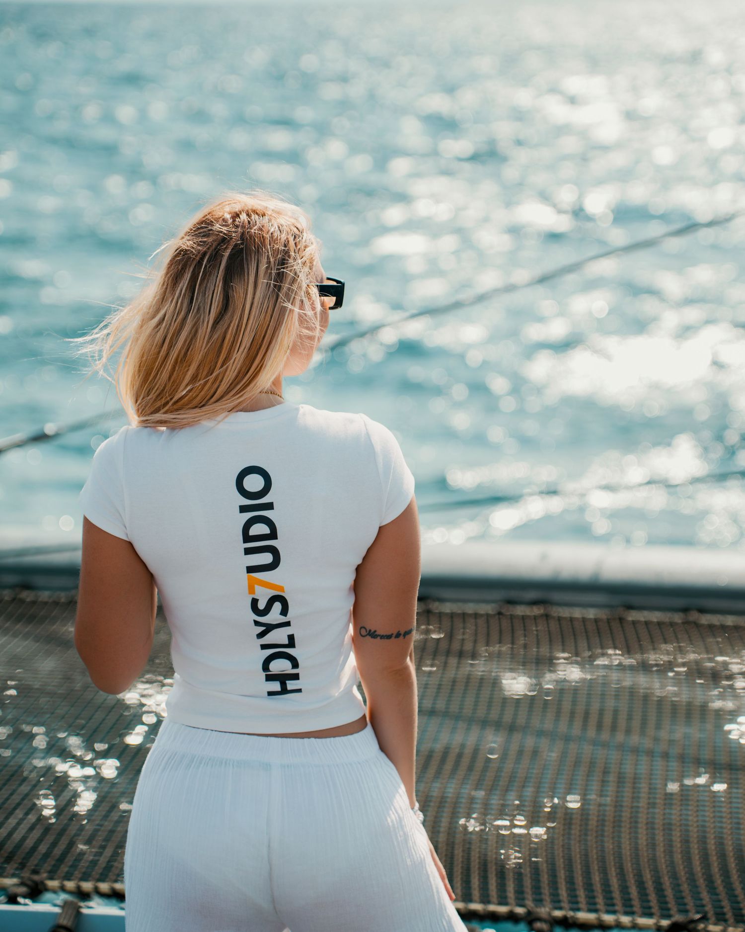 Mujer con ropa blanca de espaldas contemplando el mar