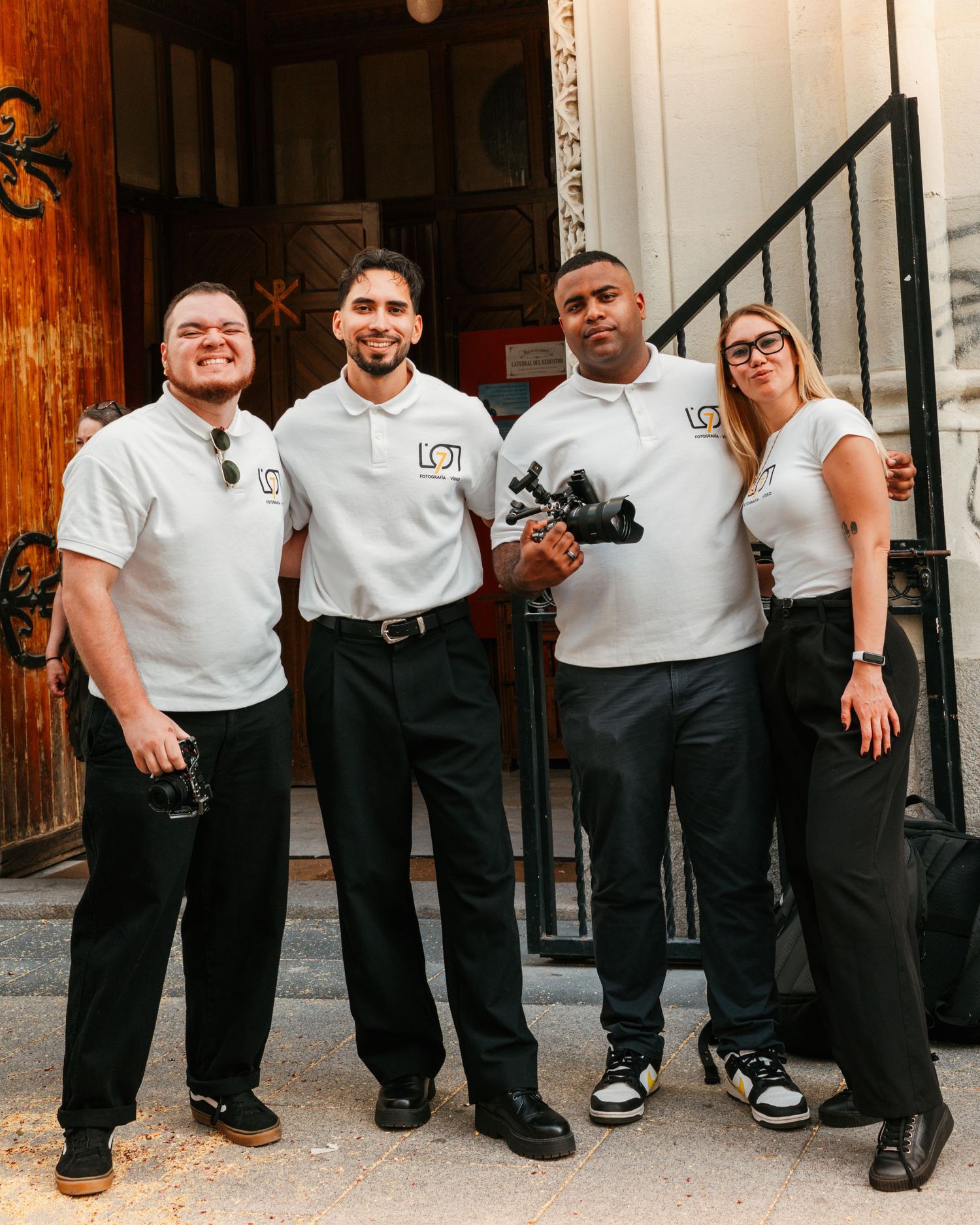 Fotografía de un equipo de fotógrafos profesionales posando con uniformes en el exterior de un local