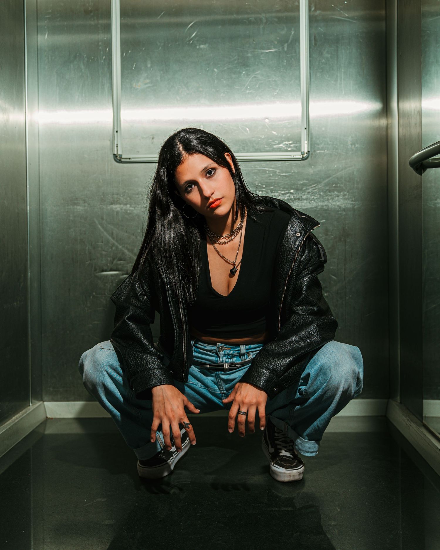 Retrato de una mujer sentada en un espacio interior de un elevador con iluminación moderna