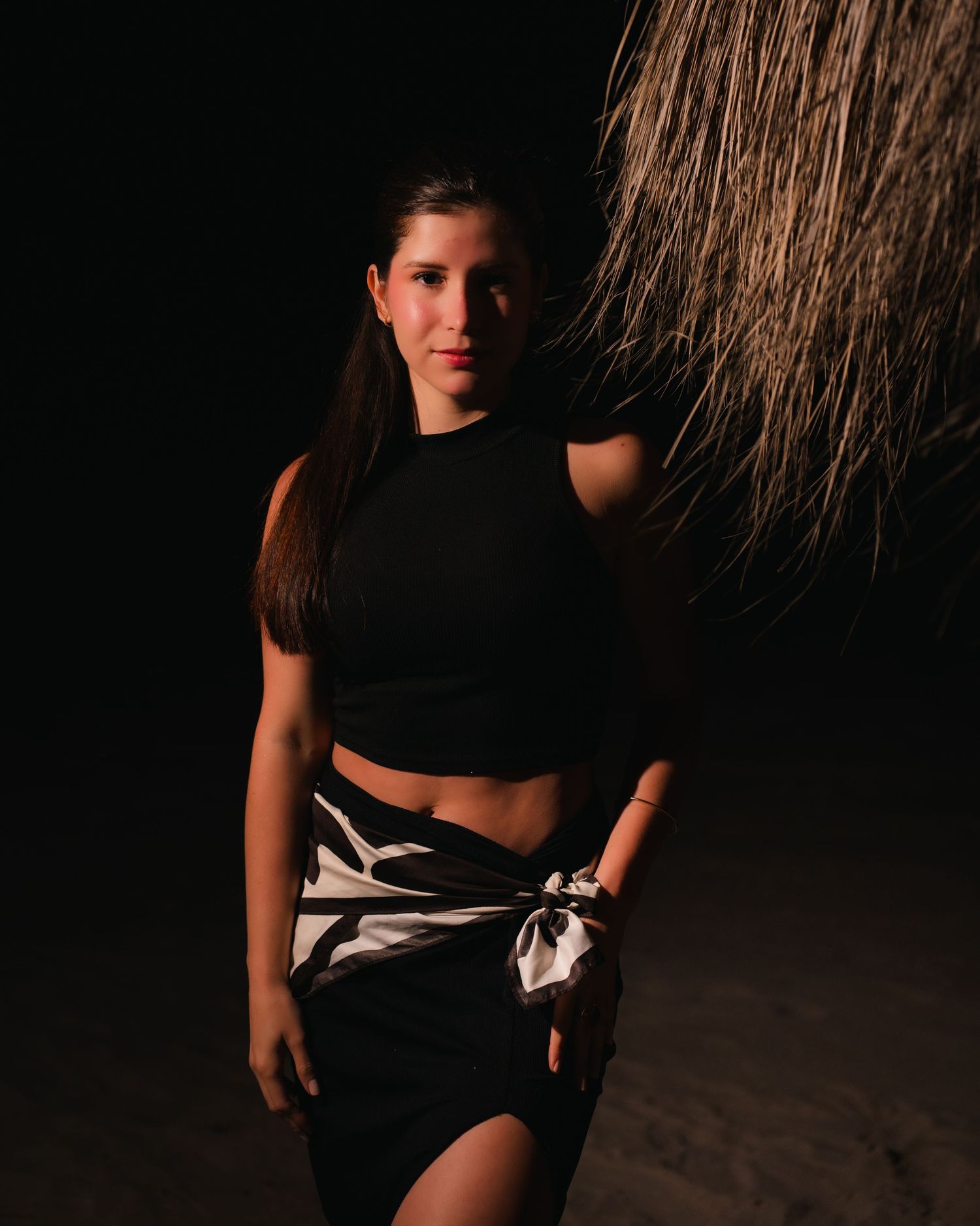 Retrato artístico de una mujer con ropa negra en un entorno oscuro de playa