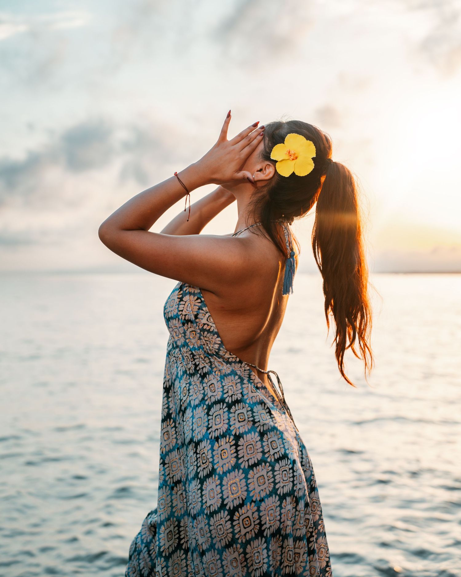 Mujer posando junto al mar con vestido estampado durante una sesión fotográfica