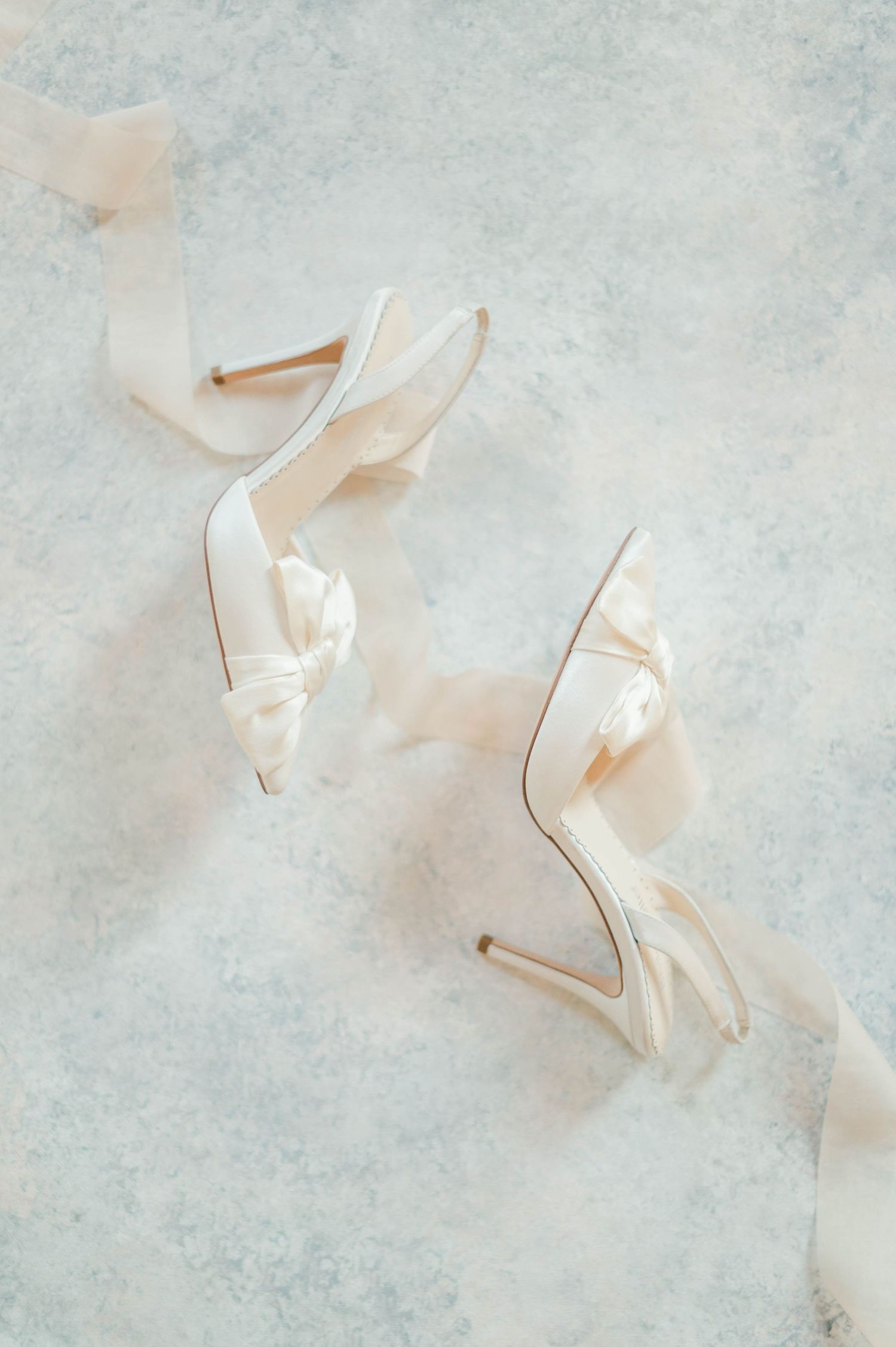 White wedding heels and ribbon on blue background.
