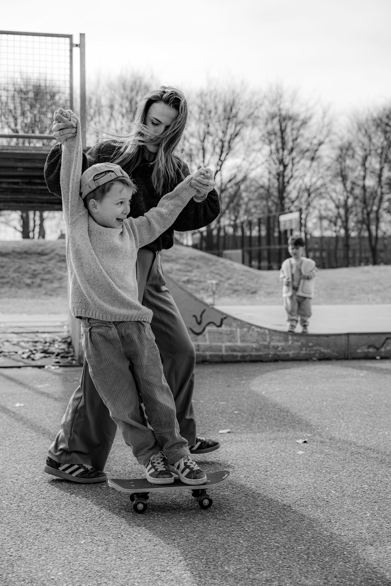 Series showing child learning to skateboard with support in black and white.