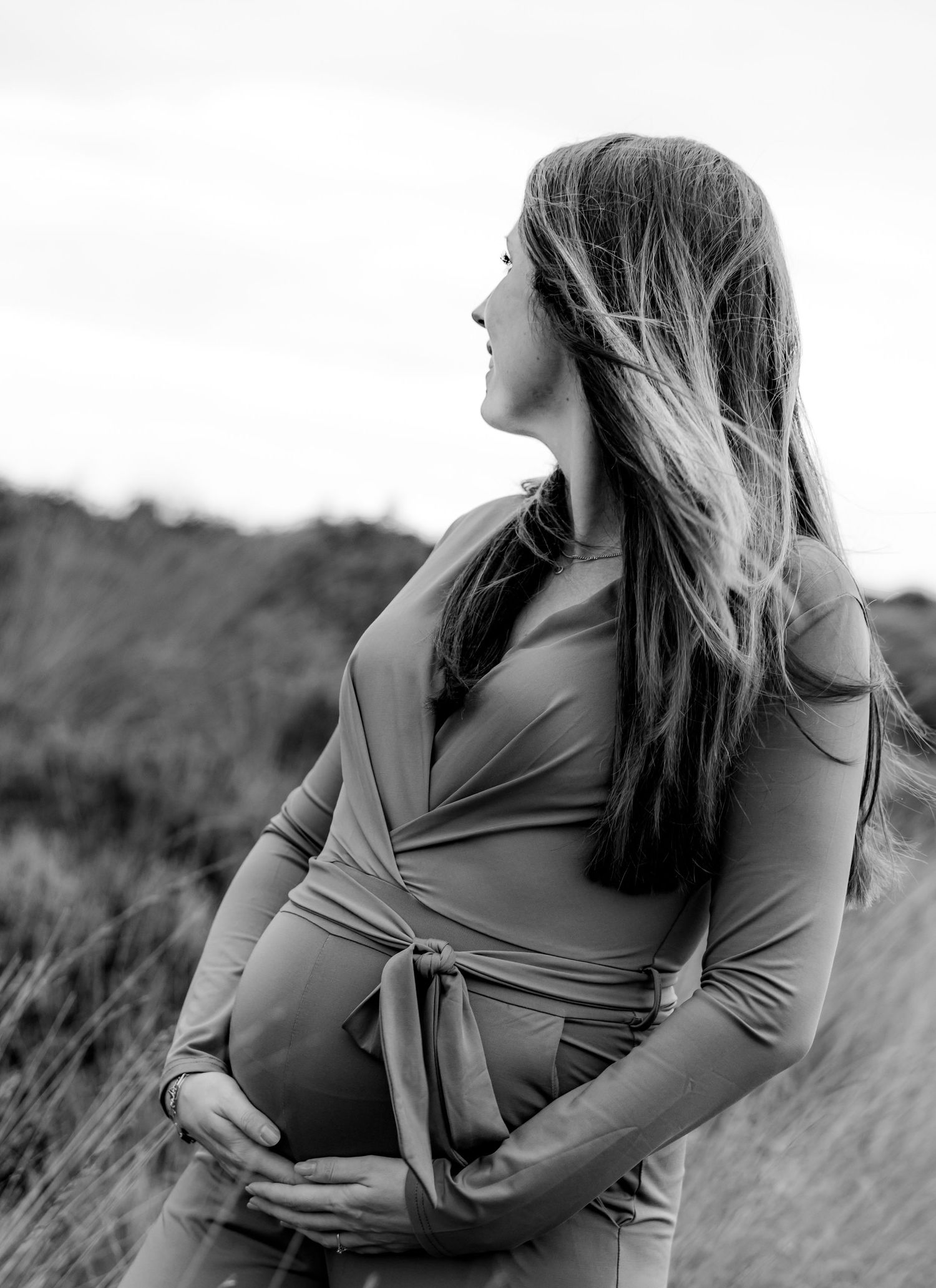 Black and white maternity photo of an expectant mother in a field.