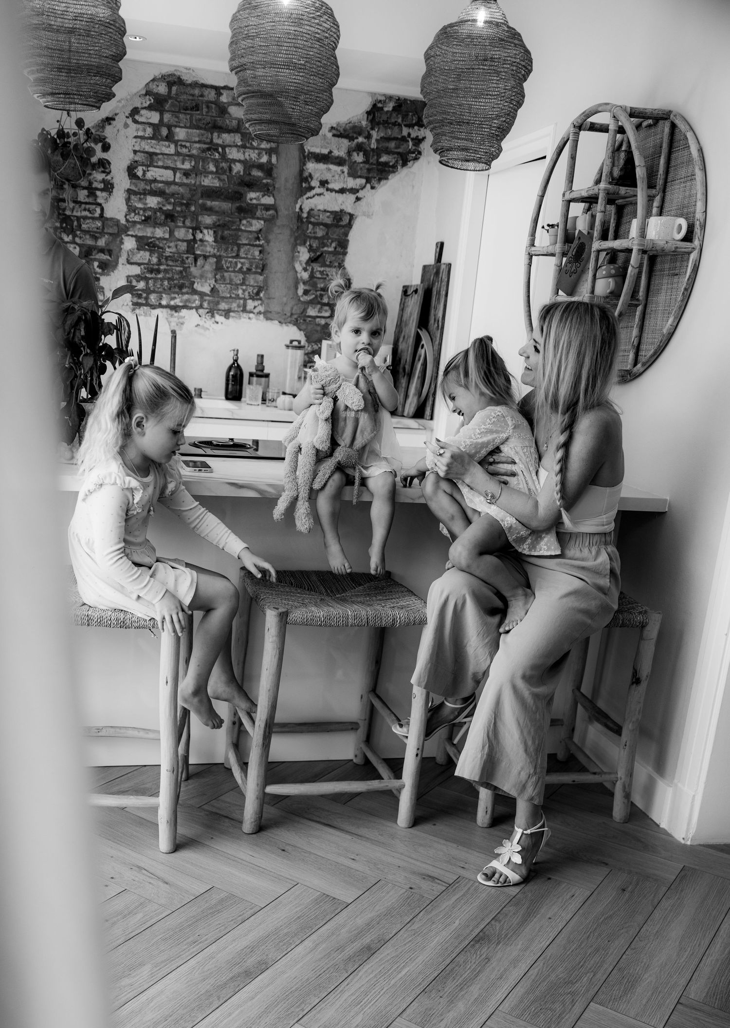 Black and white photo of family gathering at a rustic kitchen counter with pendant lights.