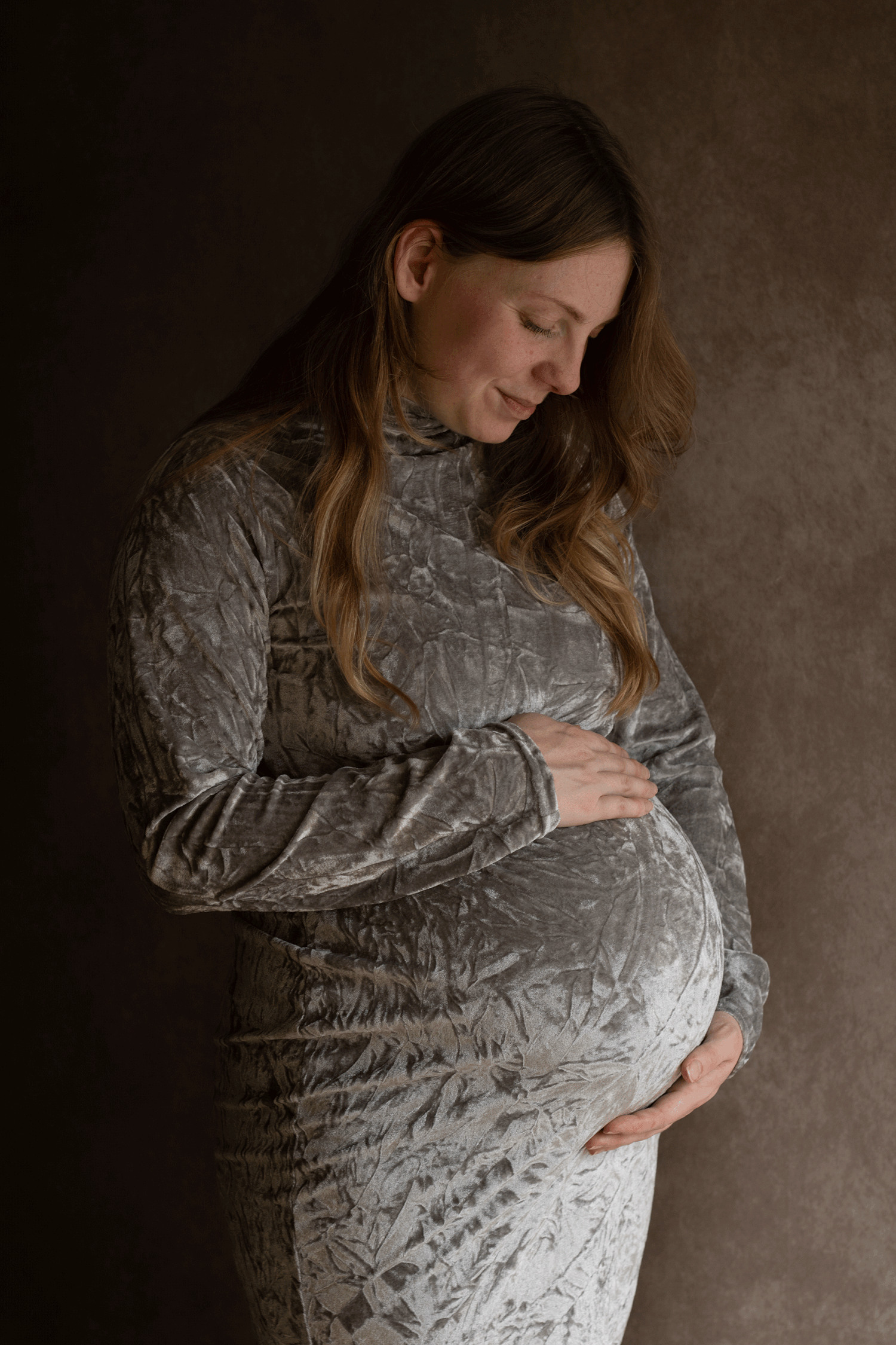 Pregnant mum looking down at bump during maternity session with Ceris Hicks Photography