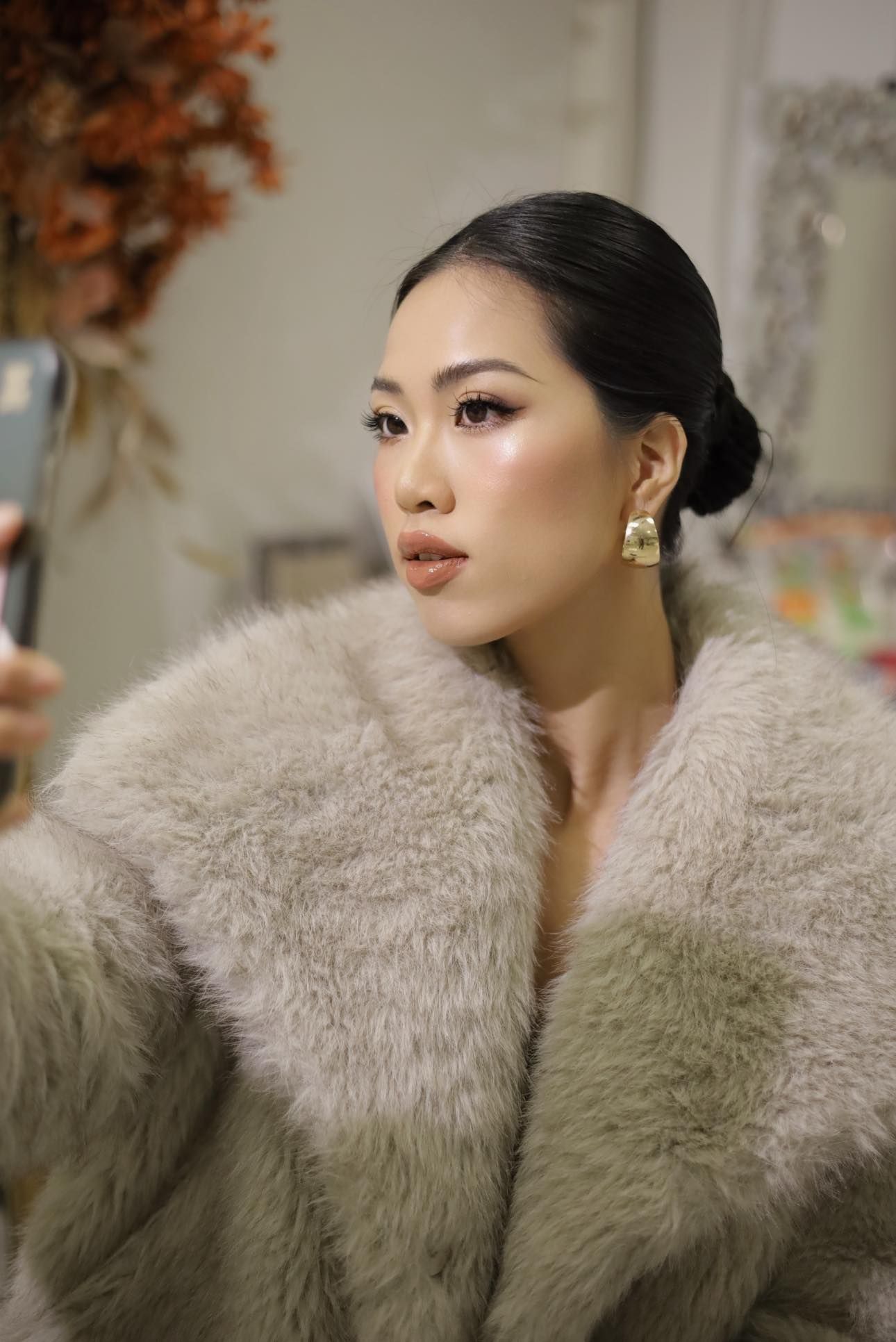 Portrait in soft lighting featuring elegant fur coat and refined evening makeup.