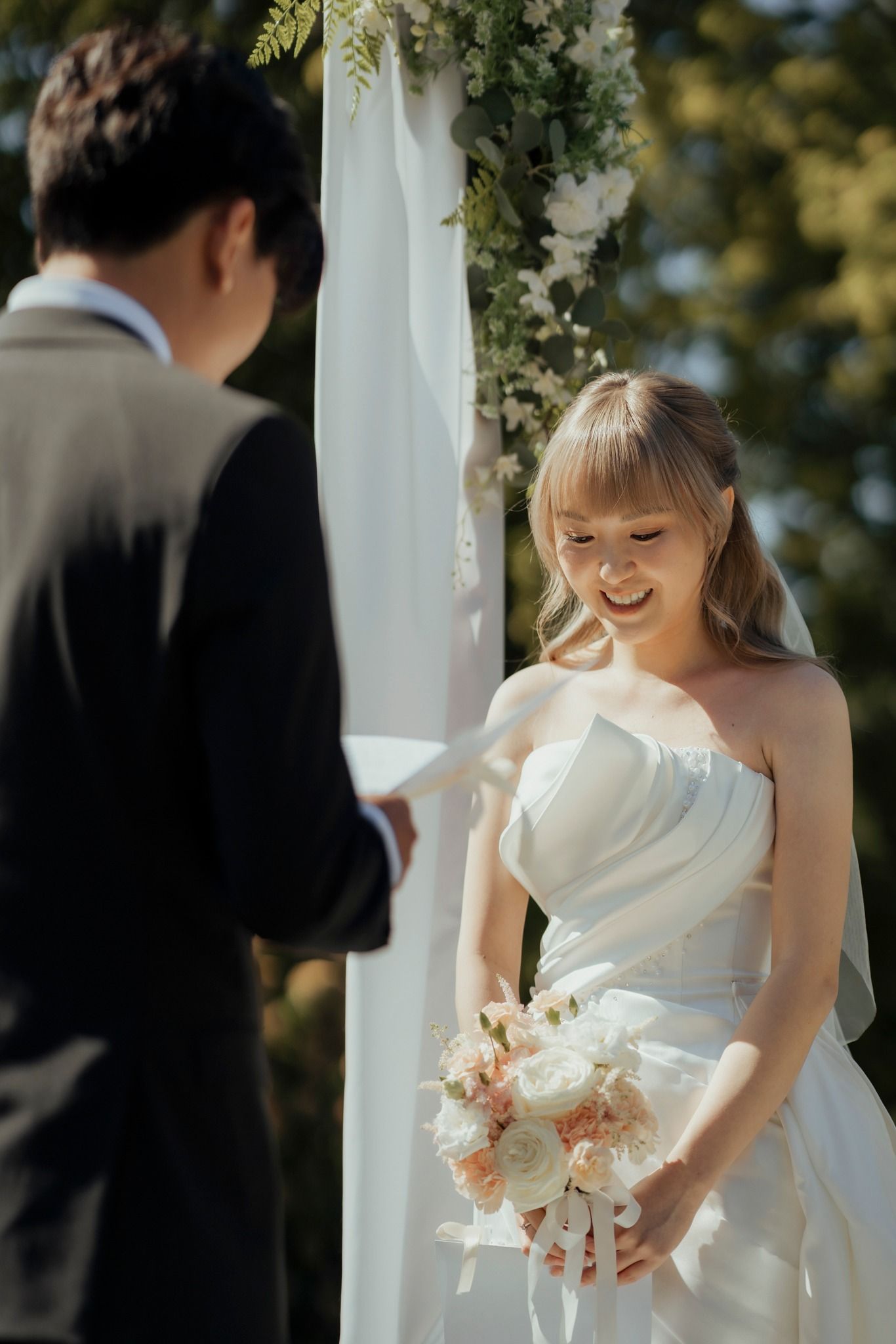 Romantic outdoor wedding ceremony with floral arch and elegant white decor.
