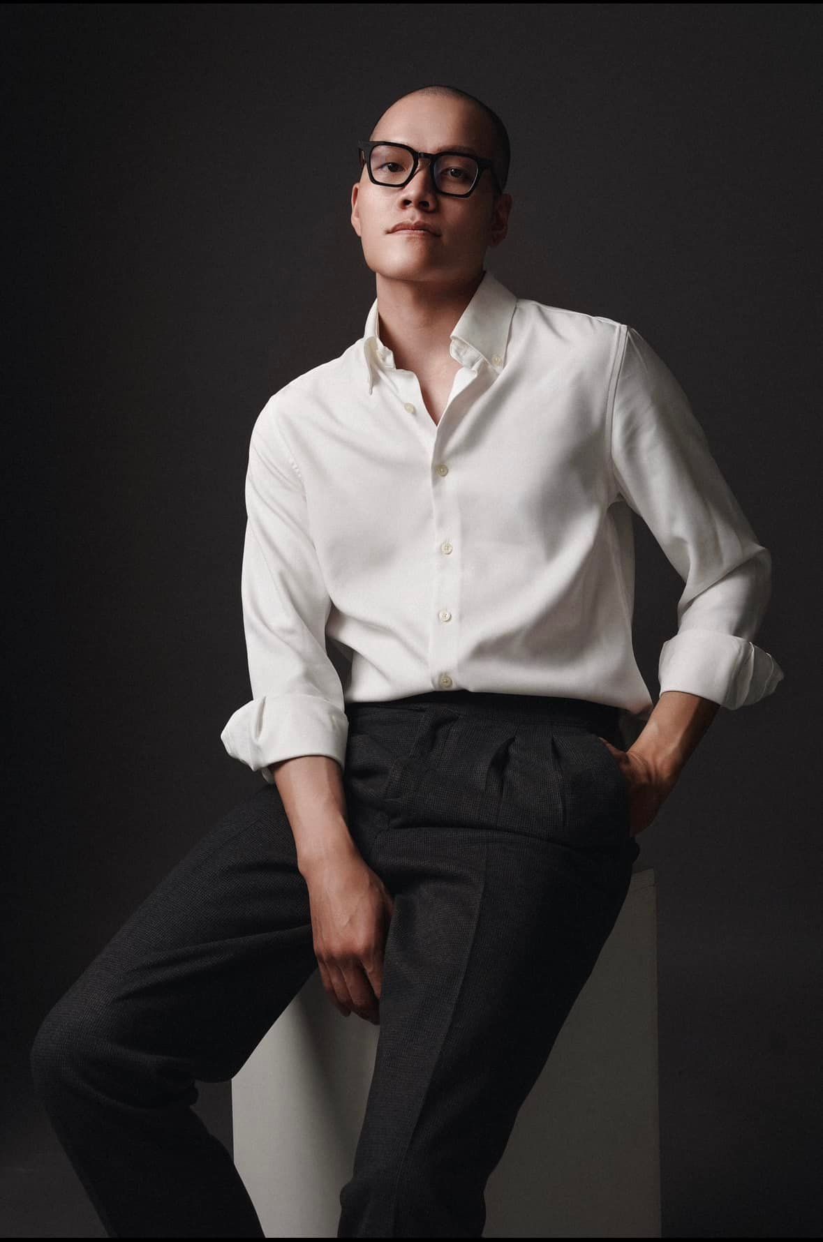 Studio portrait in dramatic lighting featuring elegant white dress shirt and black trousers.
