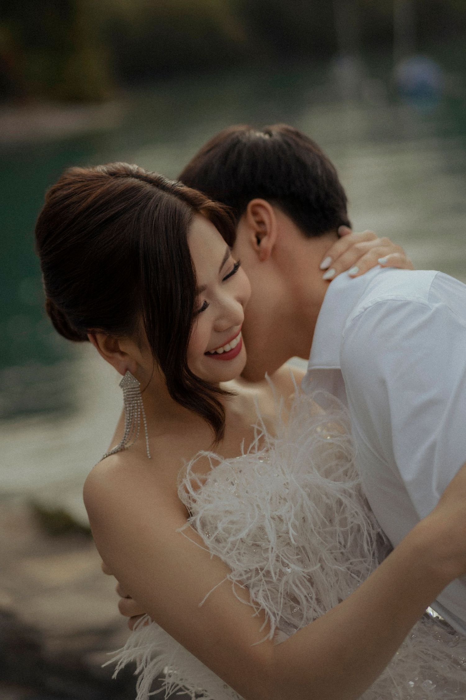 Romantic moment captured outdoors in formal attire with feathered details.