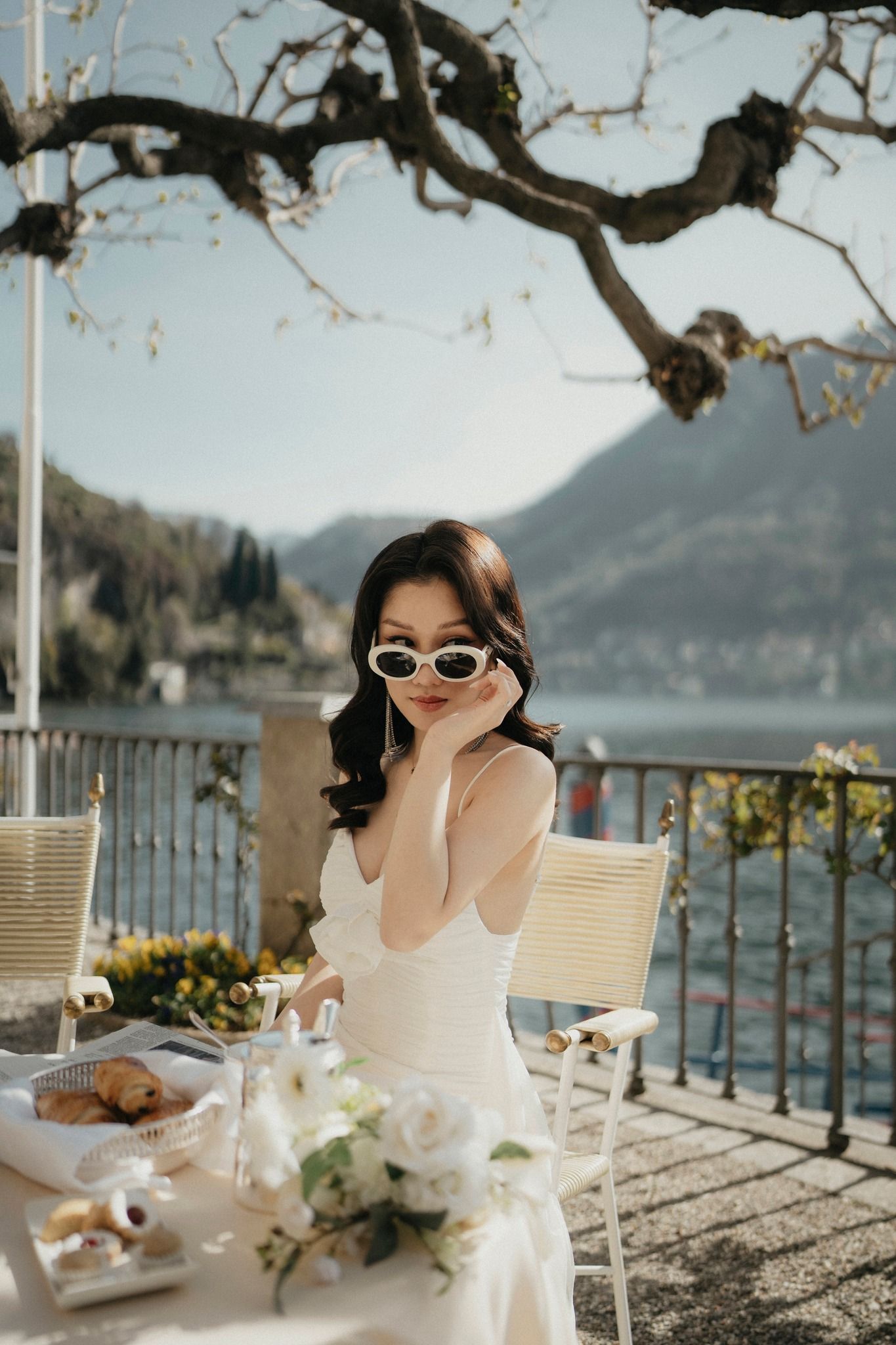Outdoor dining setup on terrace overlooking mountain lake with elegant table settings.