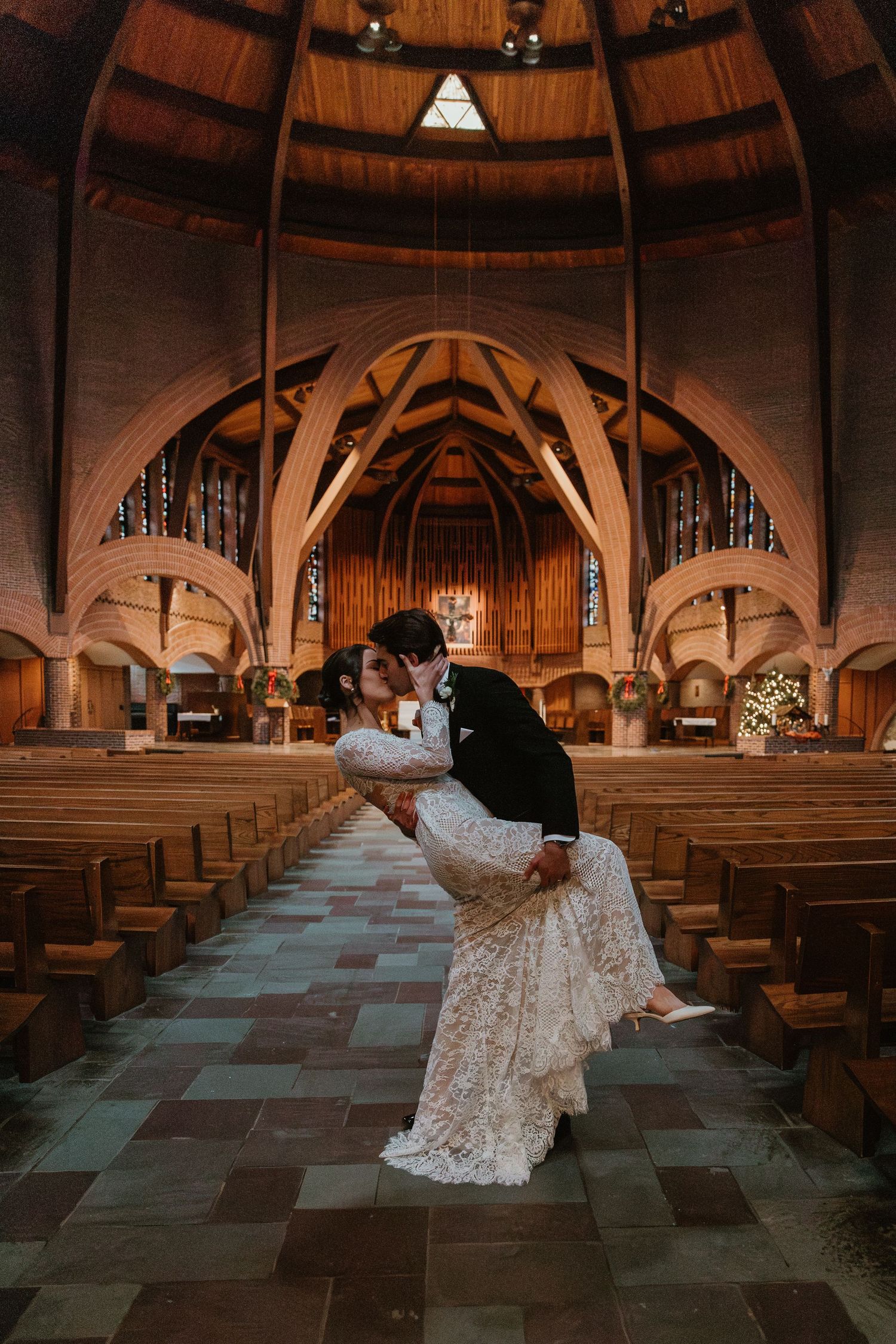 A romantic dip pose in a grand wooden church with vaulted ceilings and arches.