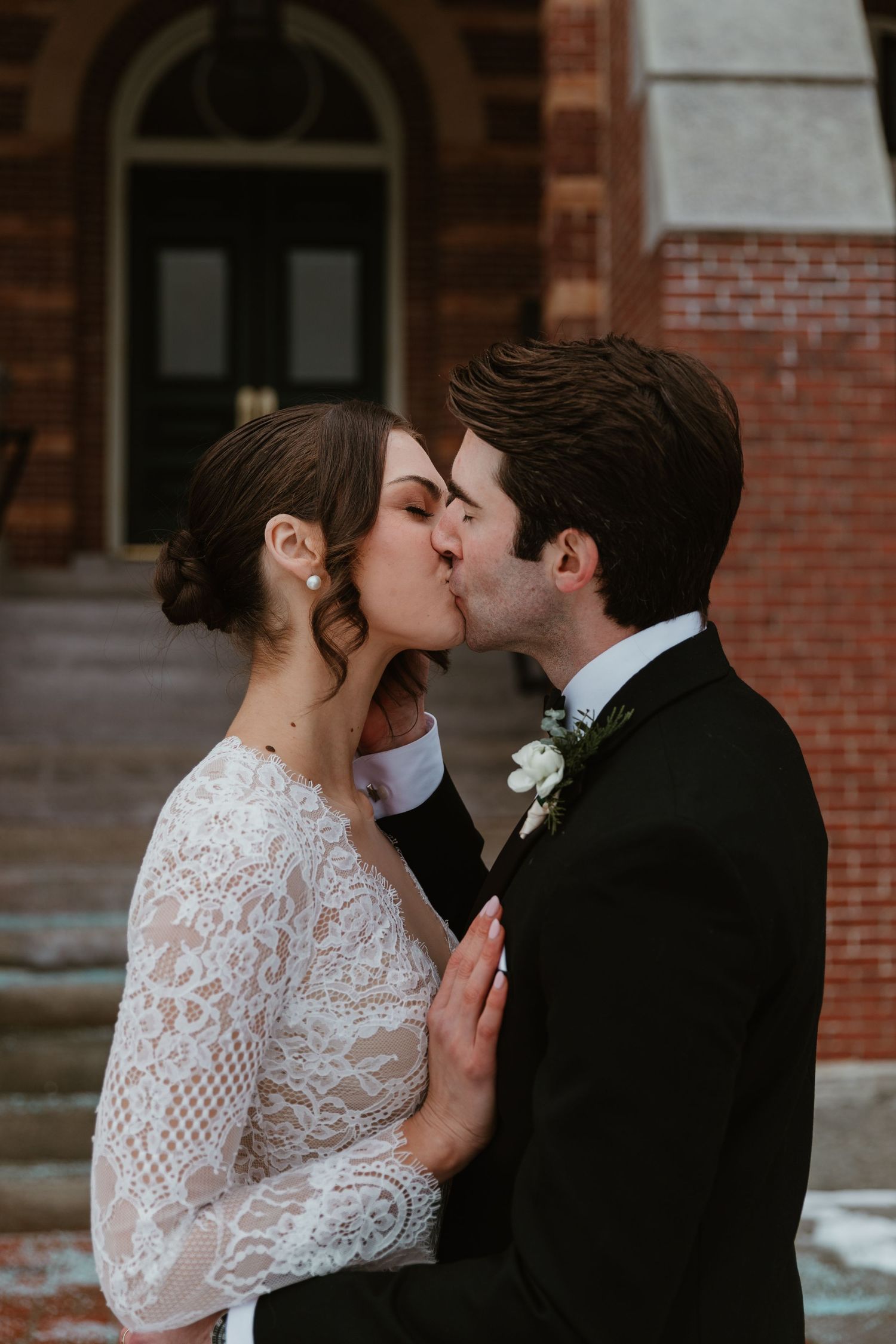 Intimate wedding moment captured against brick architecture.