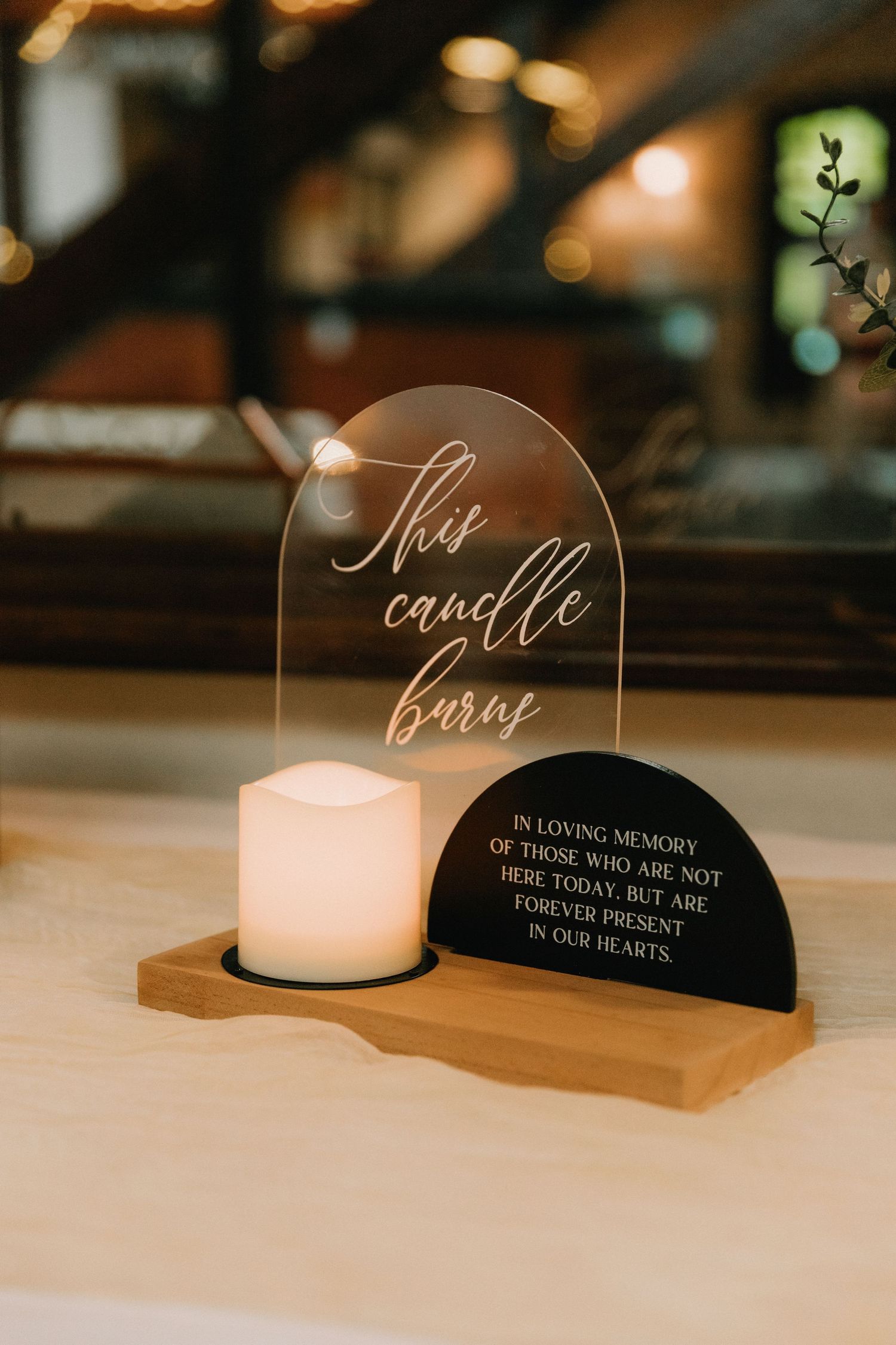 Memorial candle holders with elegant script text displayed on wooden surface at wedding reception.