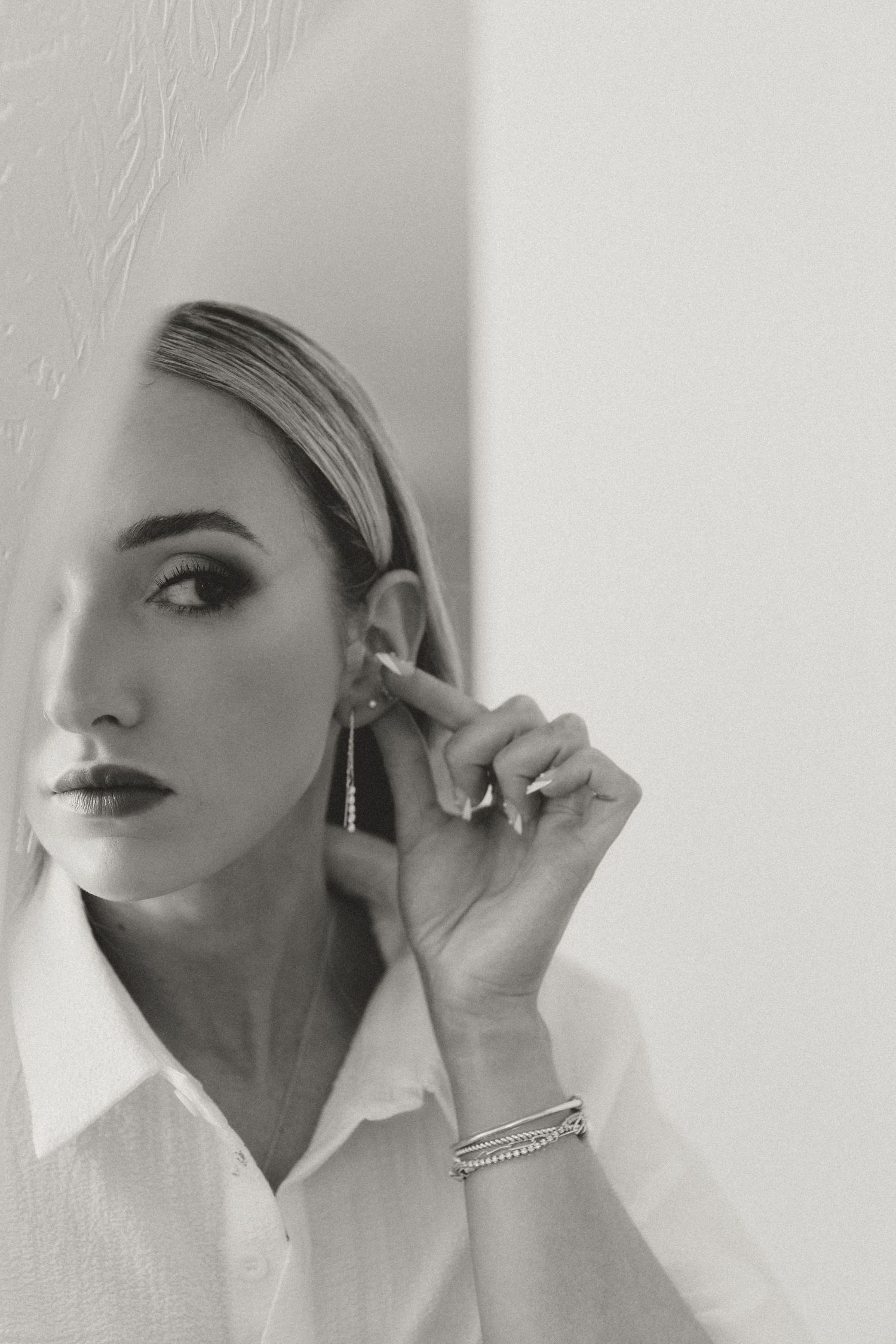Artistic black and white portrait showing jewelry and makeup details.