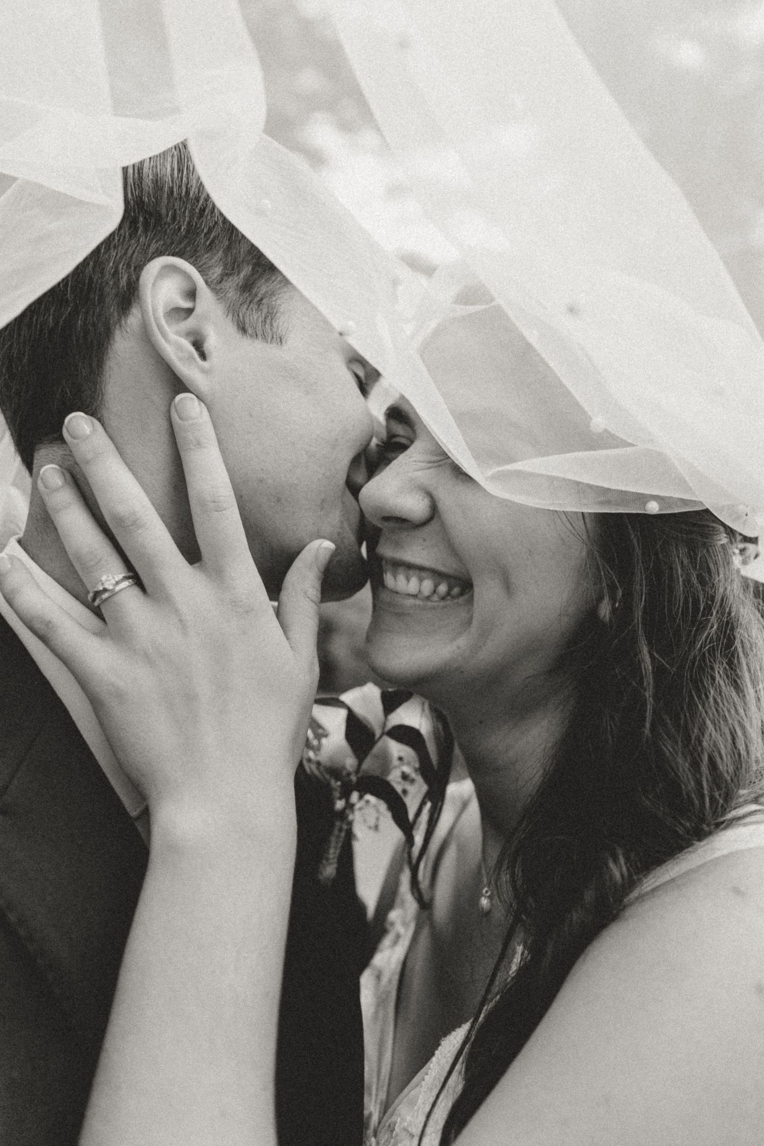 Close-up romantic moment under a delicate white veil during wedding ceremony.