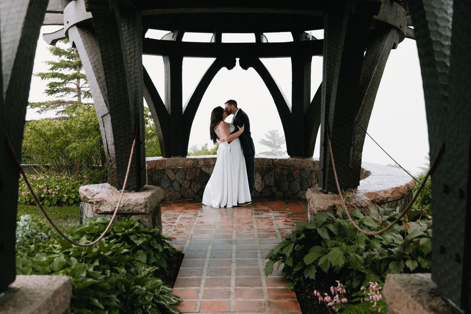 An intimate outdoor ceremony space with stone flooring and wooden beams overhead.