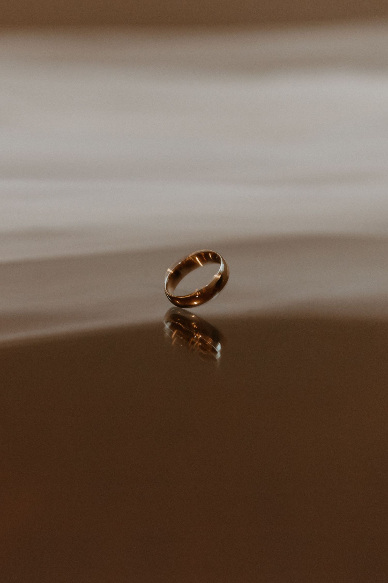 Macro photograph of a golden wedding ring with a blurred brown background.