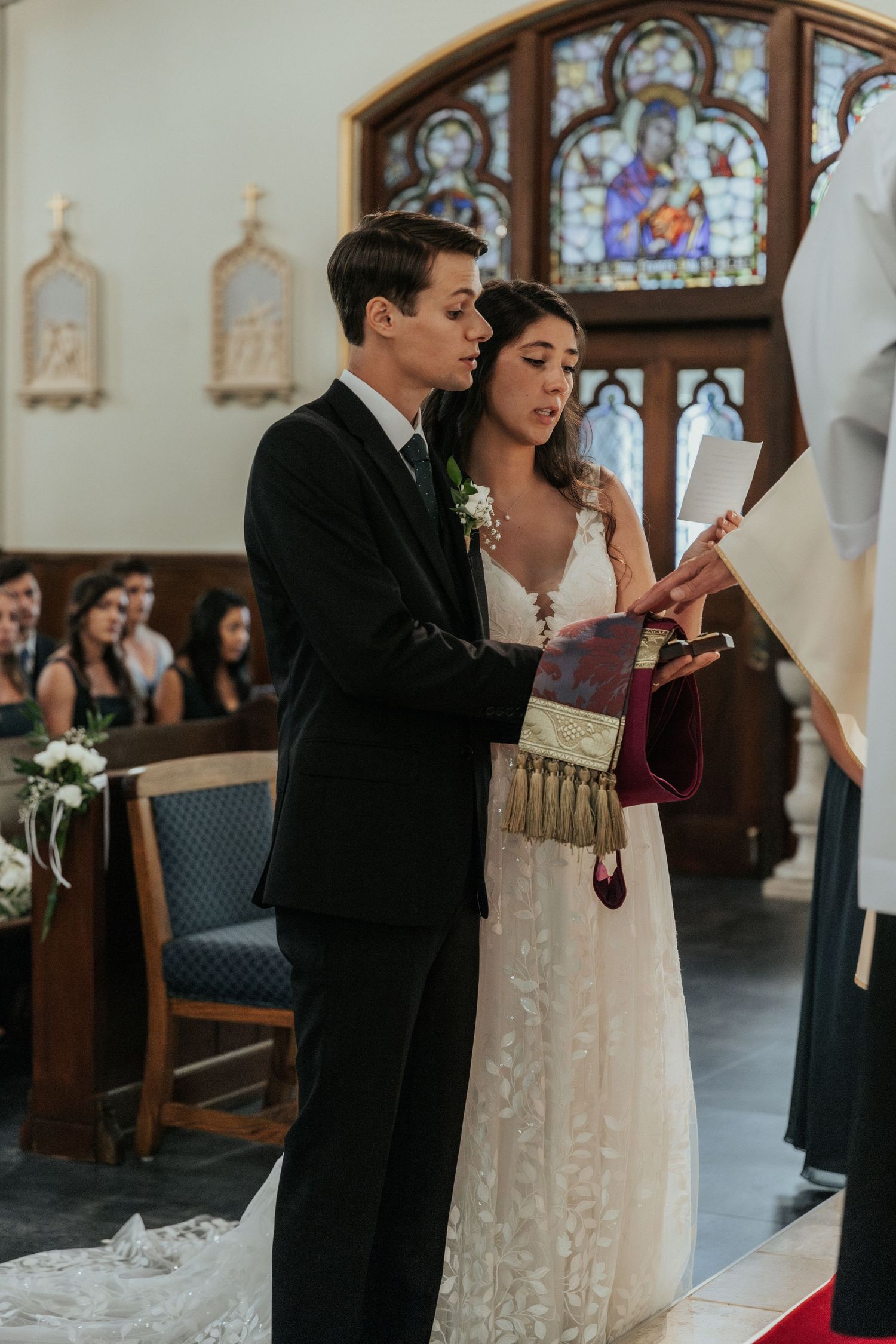 Wedding ceremony in church with stained glass windows and traditional decor.