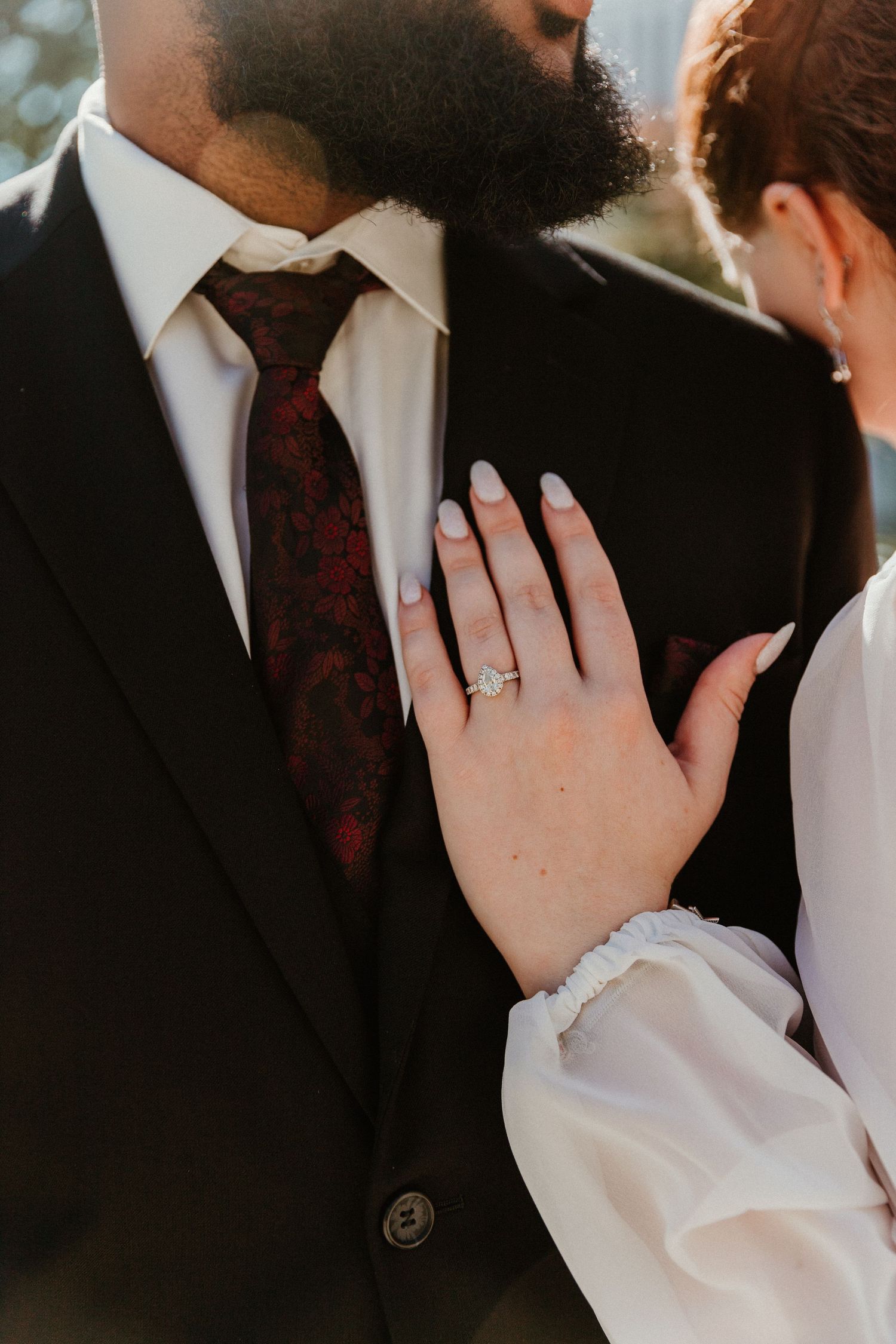 A close-up shot of a wedding ring being displayed on a hand with formal attire.
