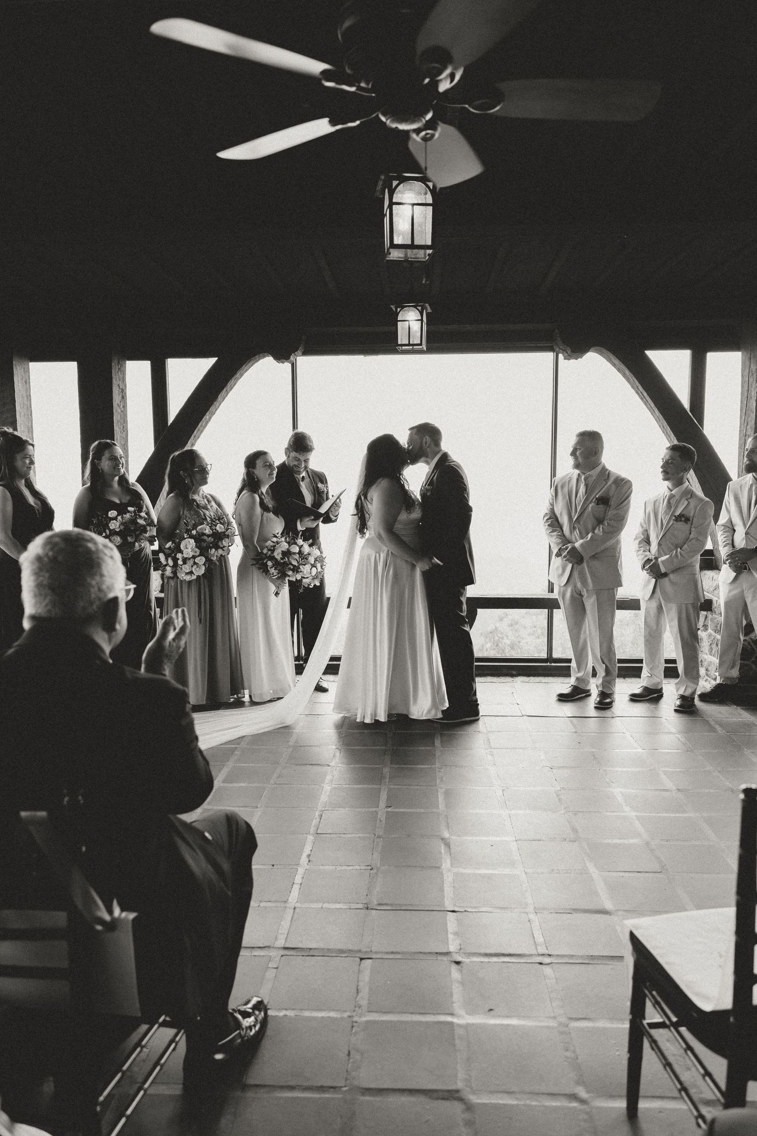 Black and white photo of wedding ceremony in a spacious room with natural lighting.