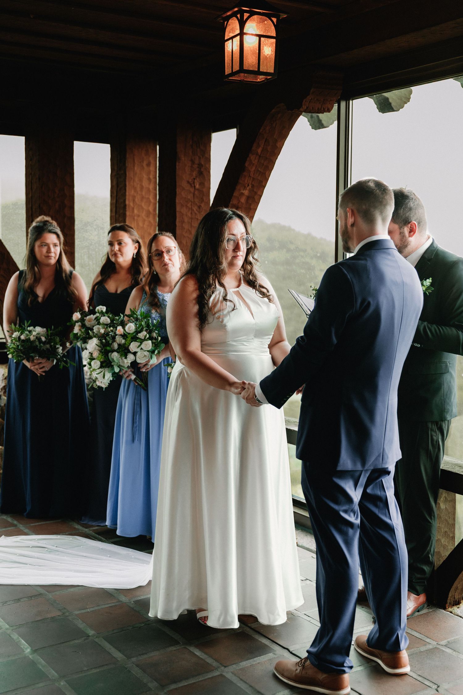 Wedding ceremony taking place in covered stone pavilion with mountain views.