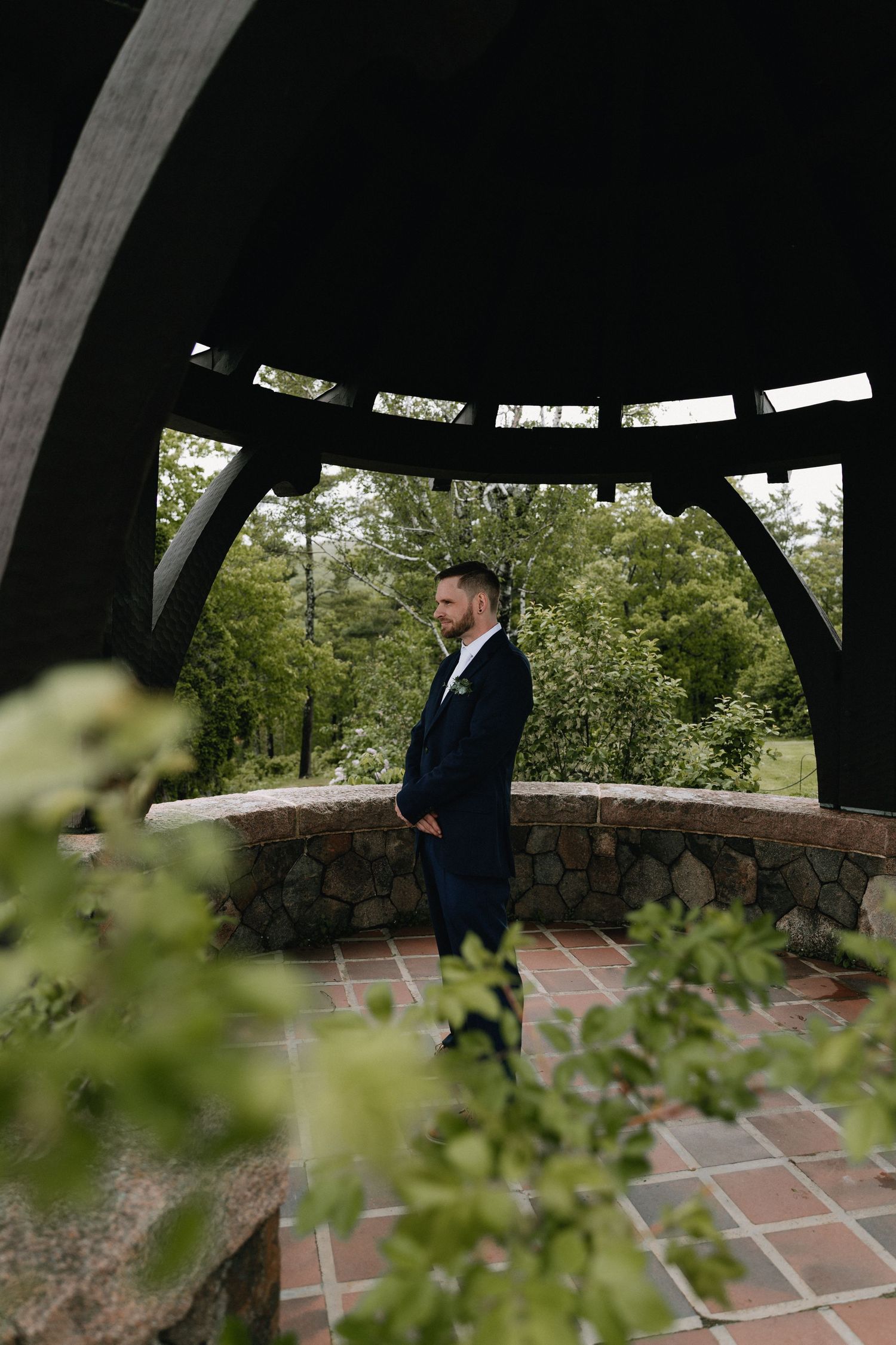 A covered outdoor pavilion with brick flooring surrounded by lush greenery creates an intimate wedding setting.