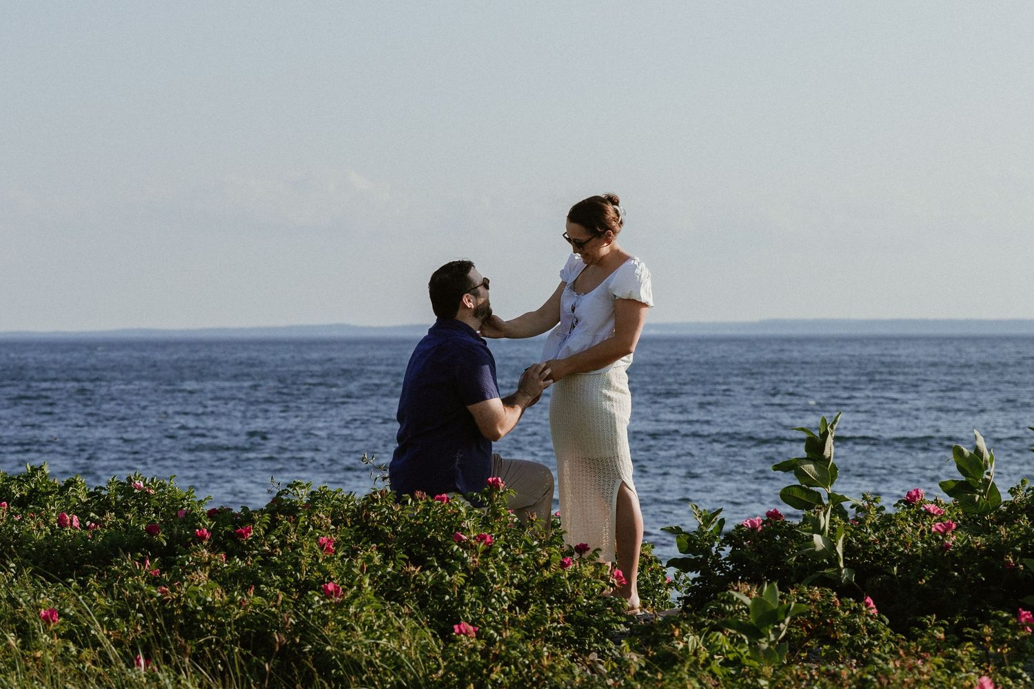 A romantic oceanside moment captured with tropical plants framing the scene.