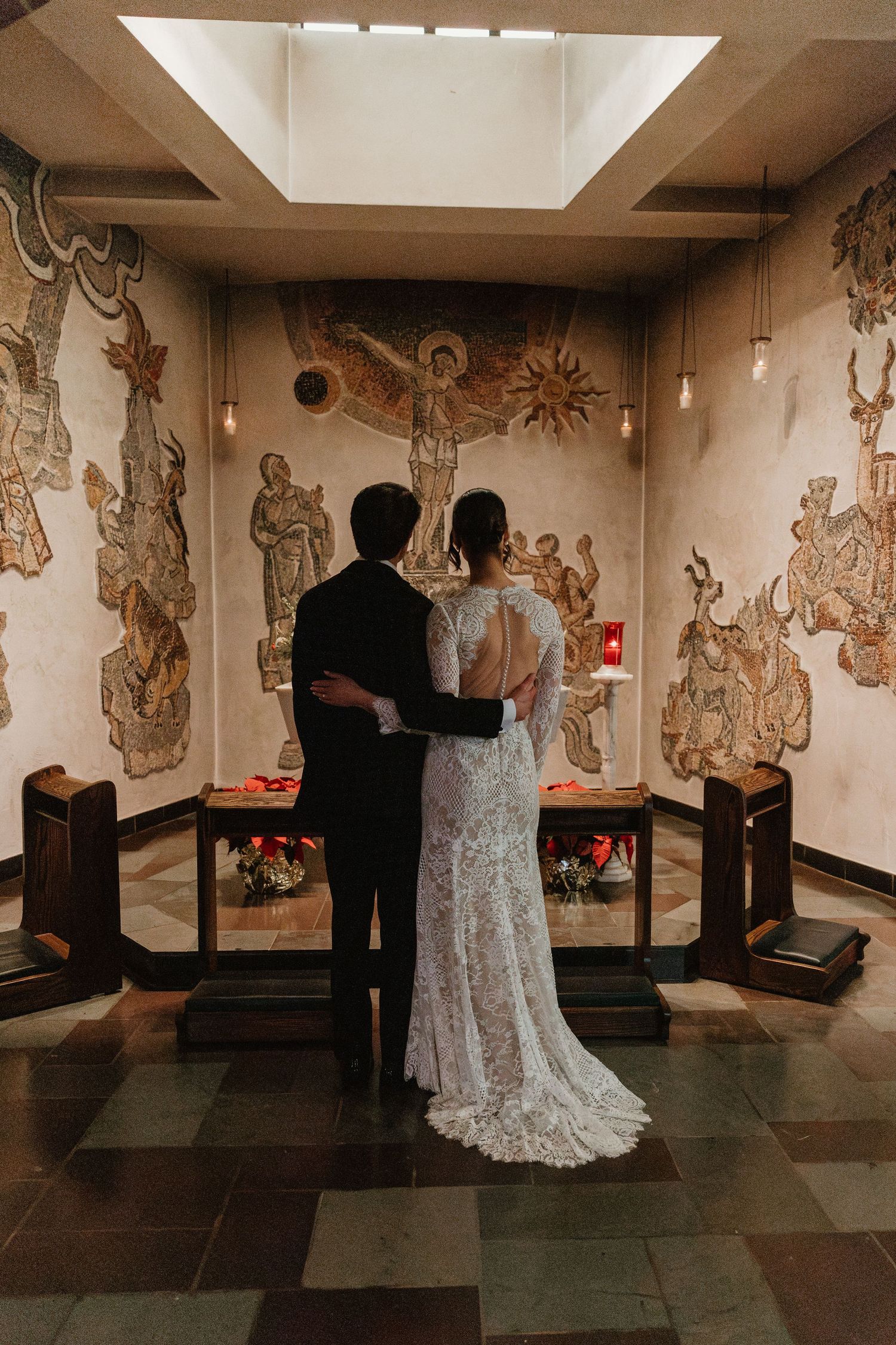 A couple dancing in an ornate room with decorative wall murals and tiled floors.