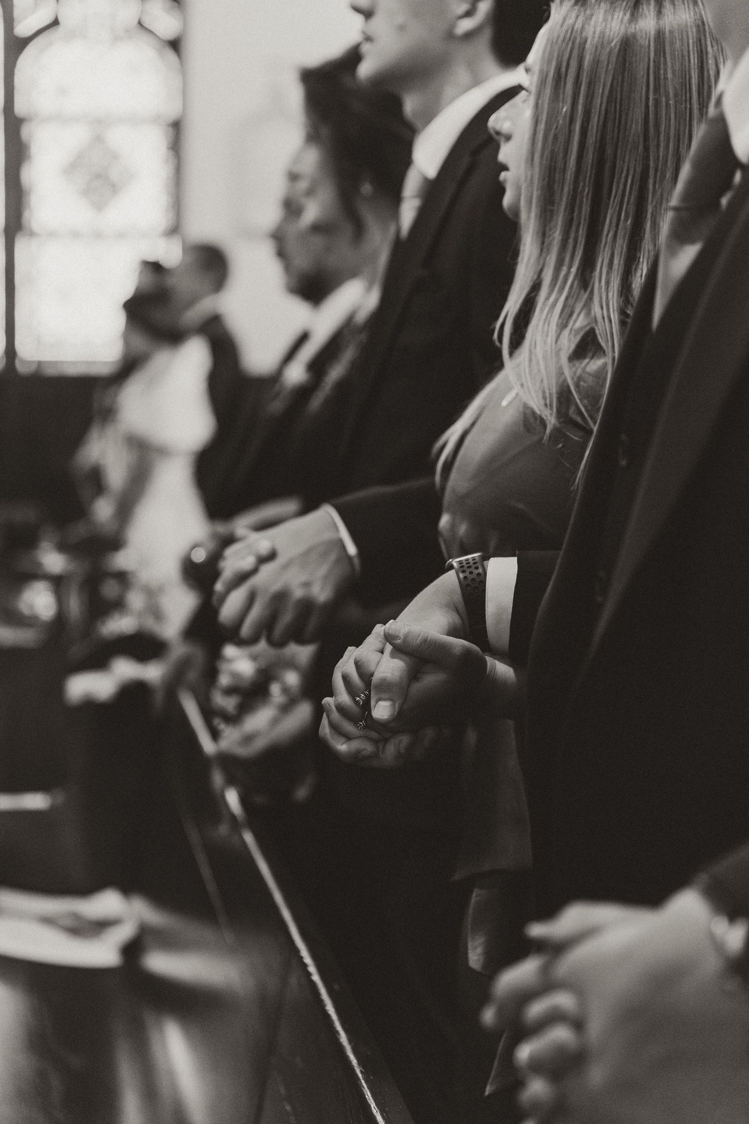 Black and white candid photo of wedding guests seated in rows during ceremony.