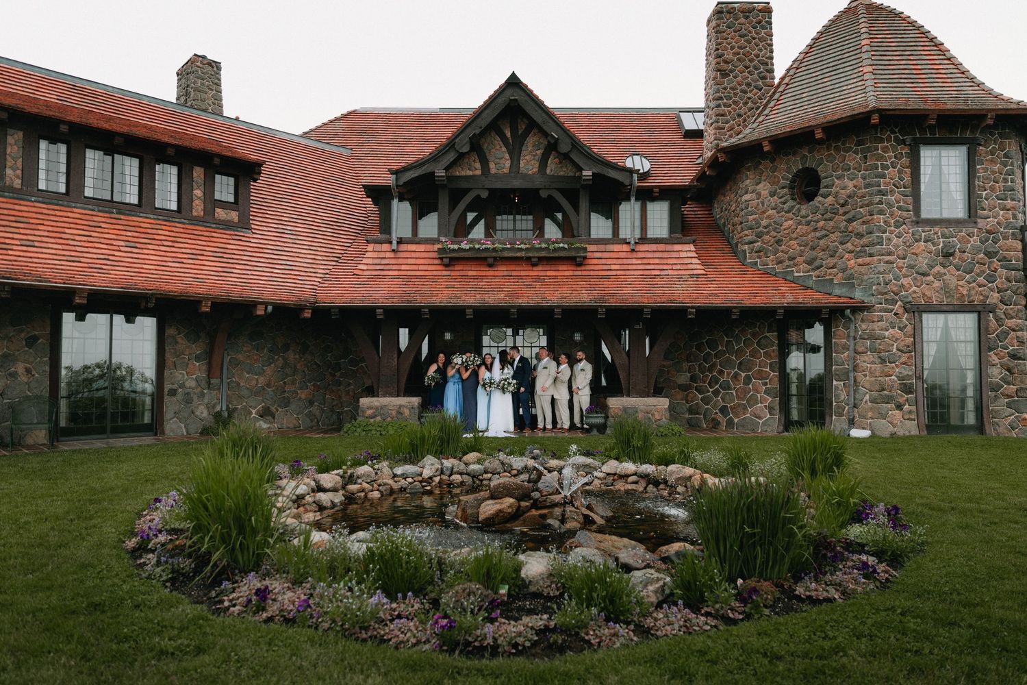 Rustic stone lodge with red roof and Tudor-style architecture set against natural landscape.