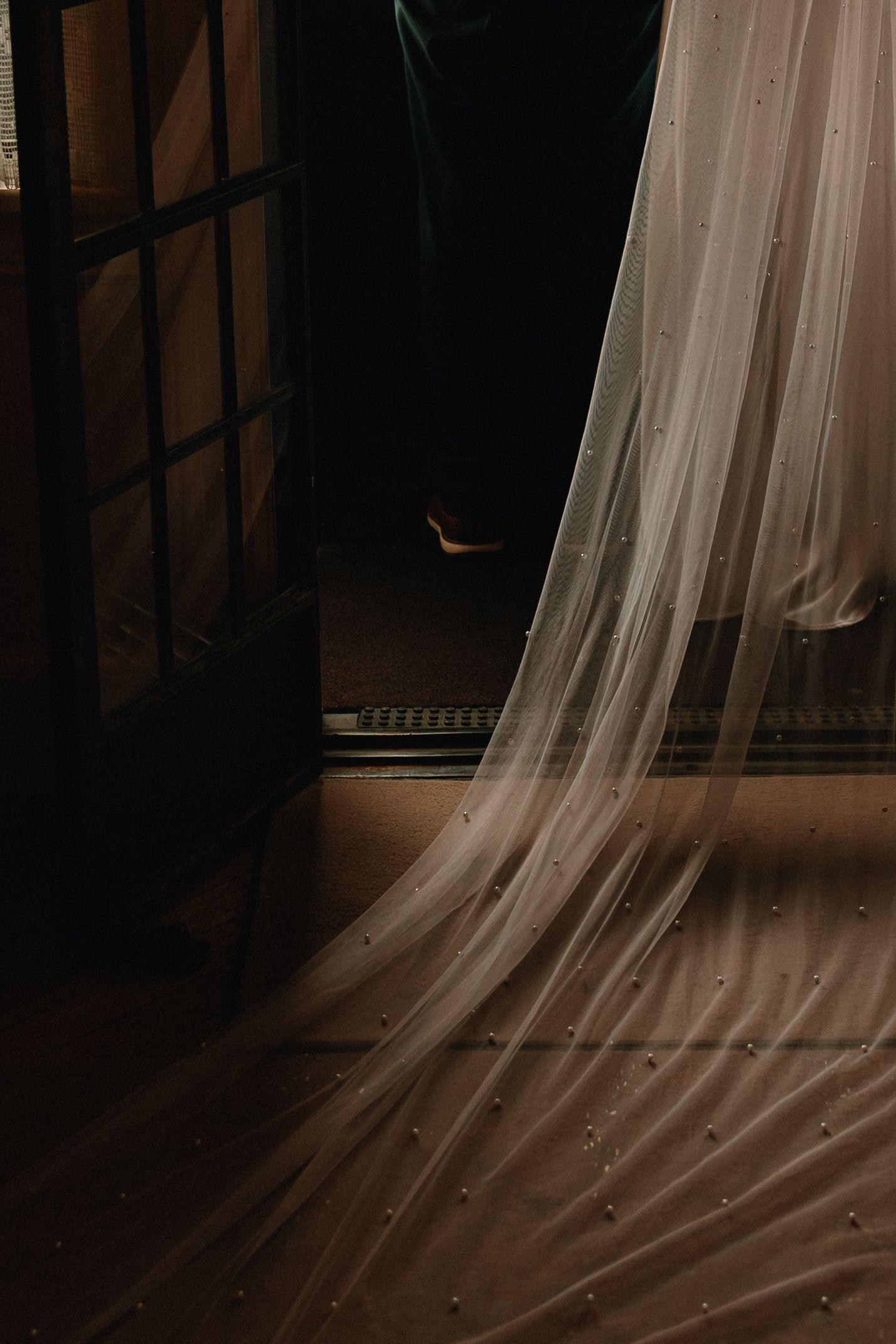 Flowing white curtains create an ethereal atmosphere in a dimly lit room with dark wooden details.