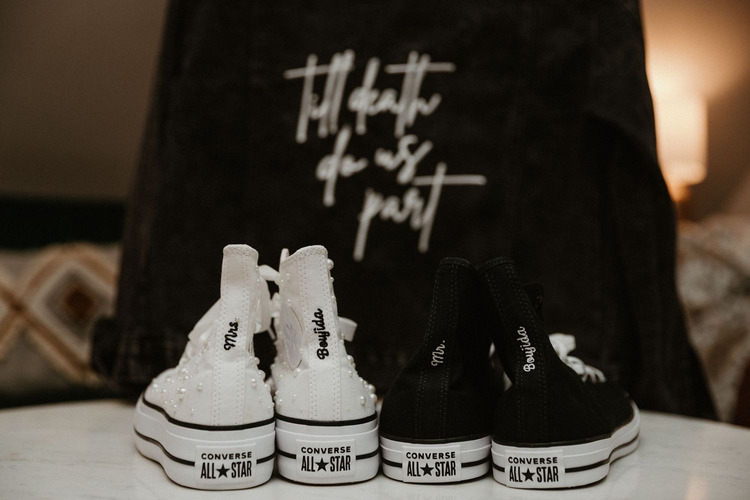 Four pairs of black and white Converse sneakers arranged in a row against a dark background.