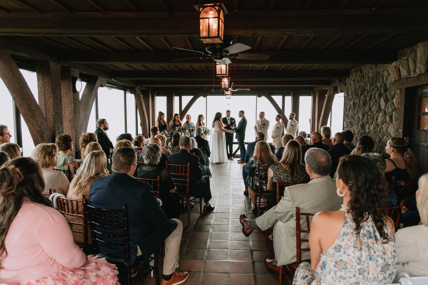 Wedding ceremony in progress under covered outdoor venue with lantern lighting.