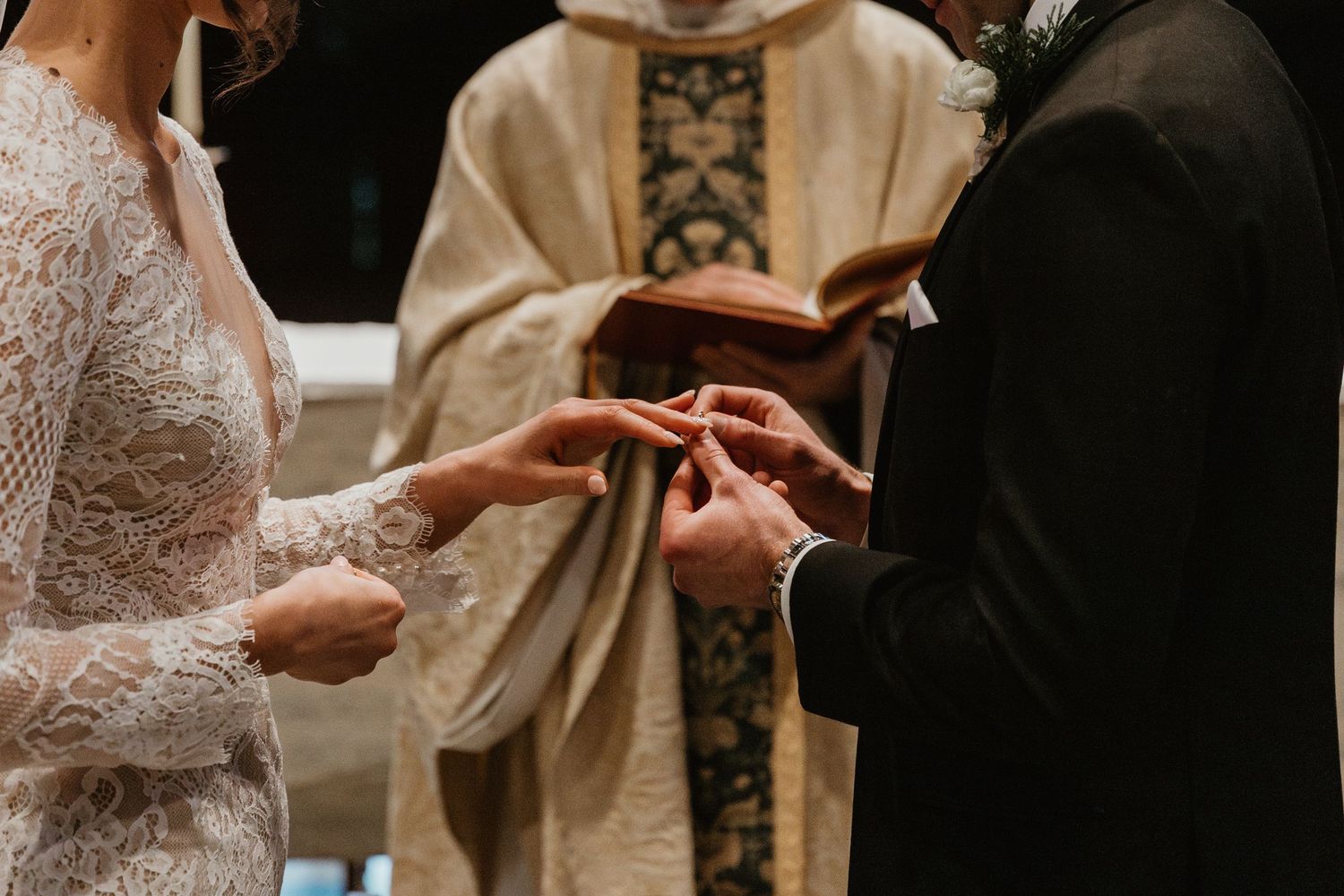 Close-up of hands exchanging wedding rings during a traditional church ceremony.