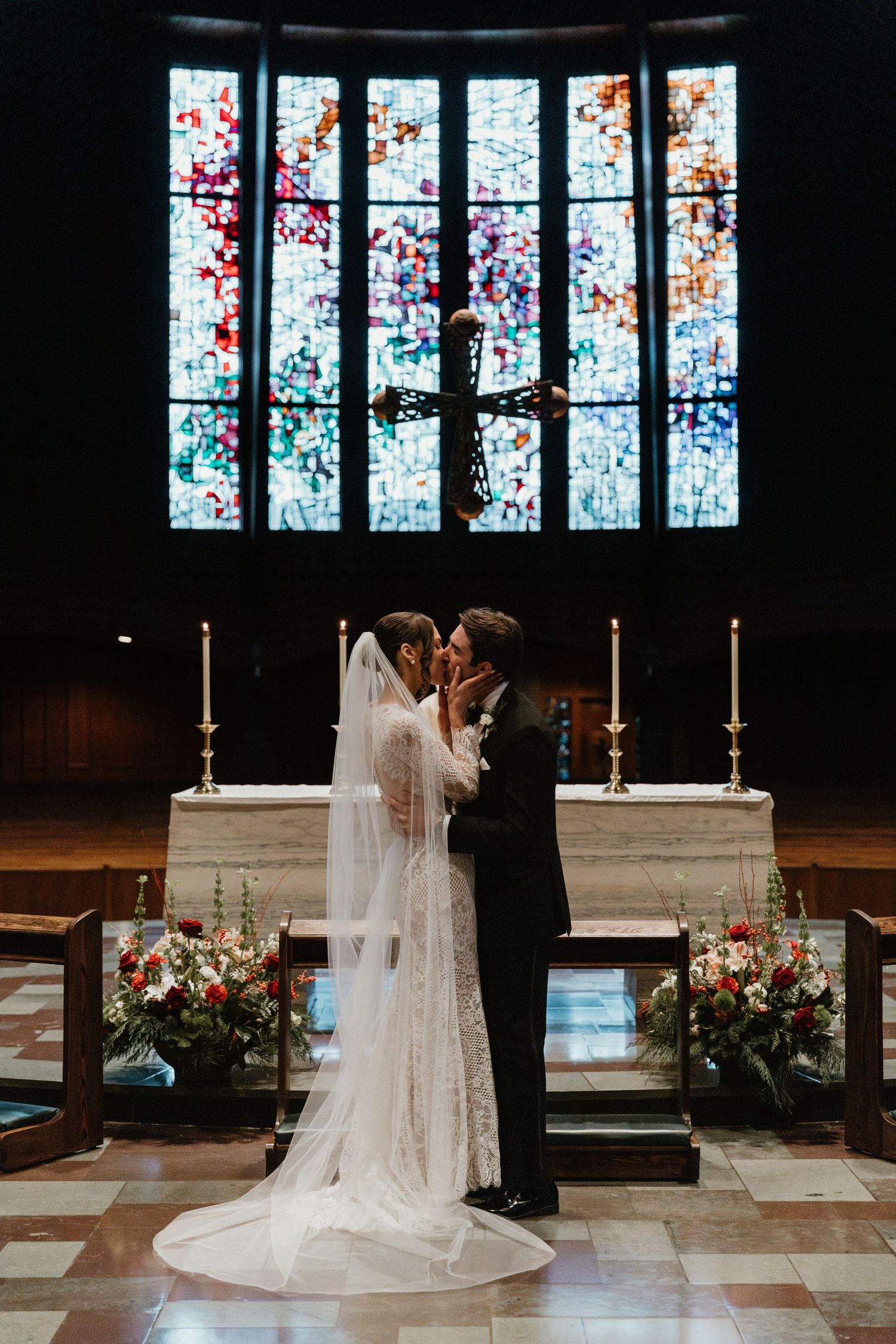 Newlyweds share their first kiss at the altar beneath a stunning stained glass window.